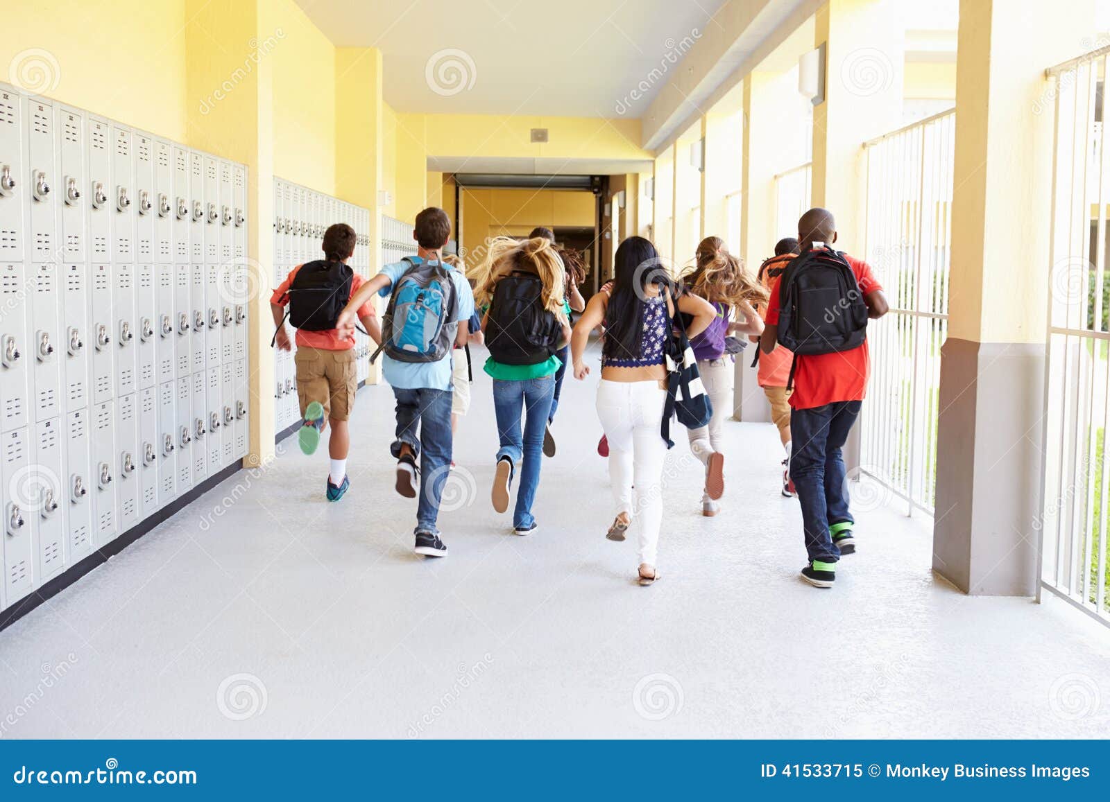group of high school students running along corridor