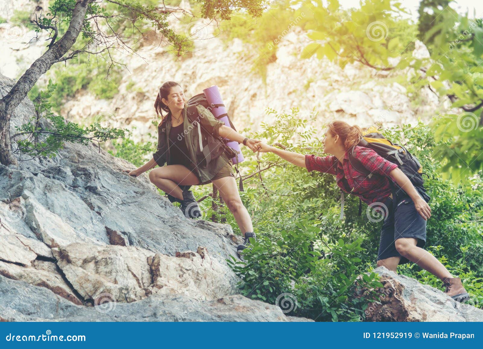 group hiker woman helping her friend climb up the last section of sunset in mountains. traveler teamwork walking in outdoor lifest