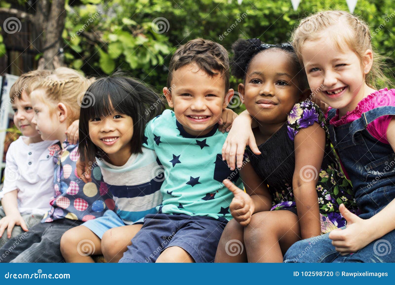 group of kindergarten kids friends arm around sitting and smiling fun