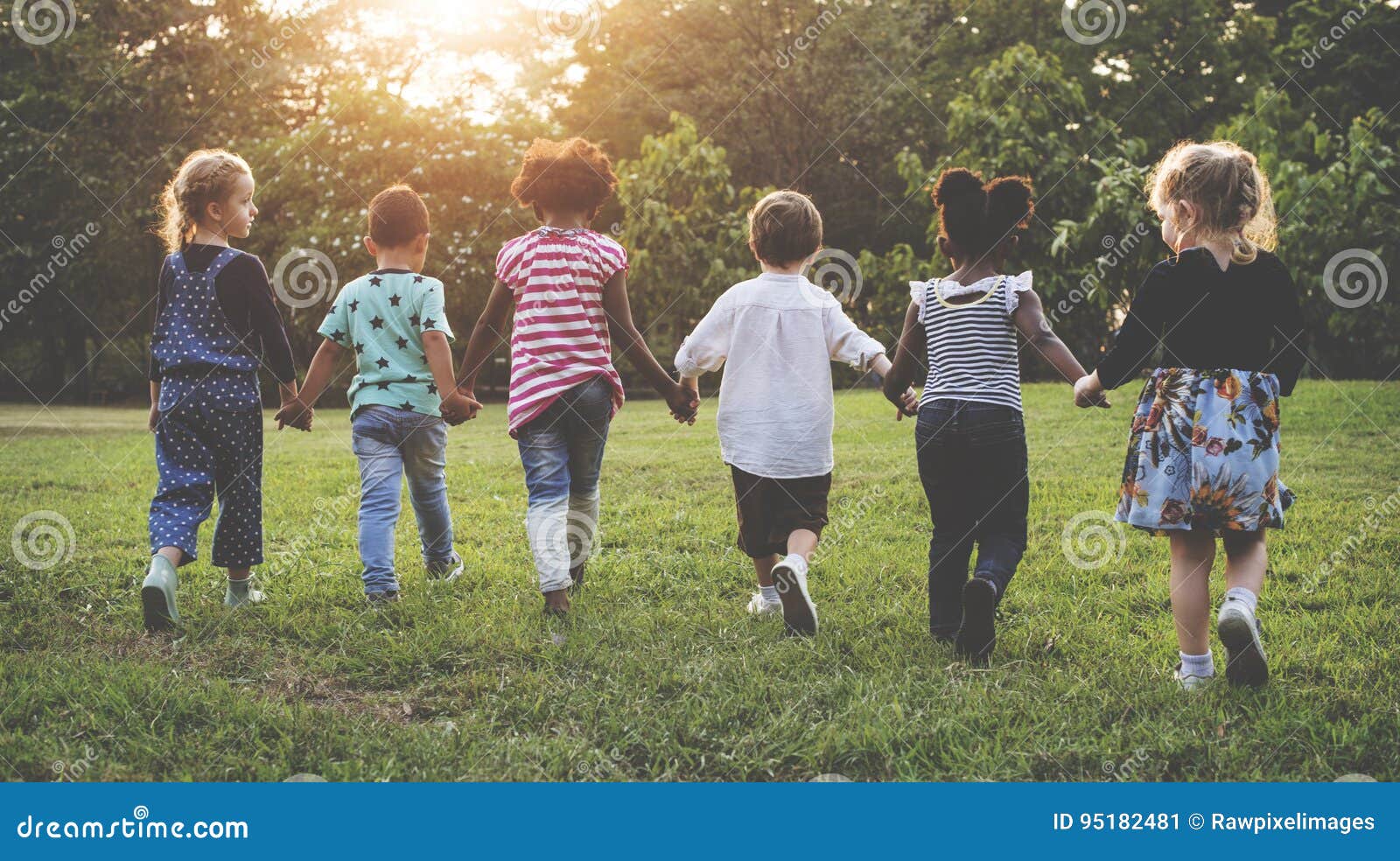 group of kindergarten kids friends holding hands playing at park