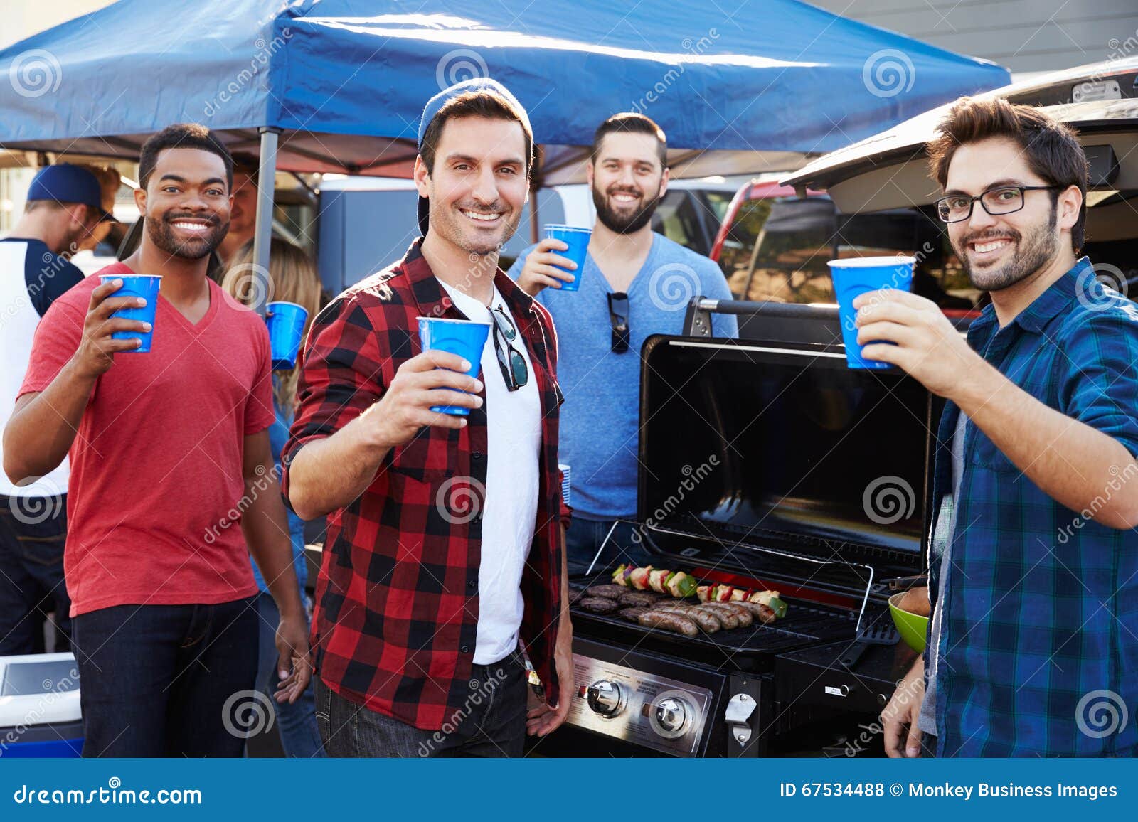 group of male sports fans tailgating in stadium car park