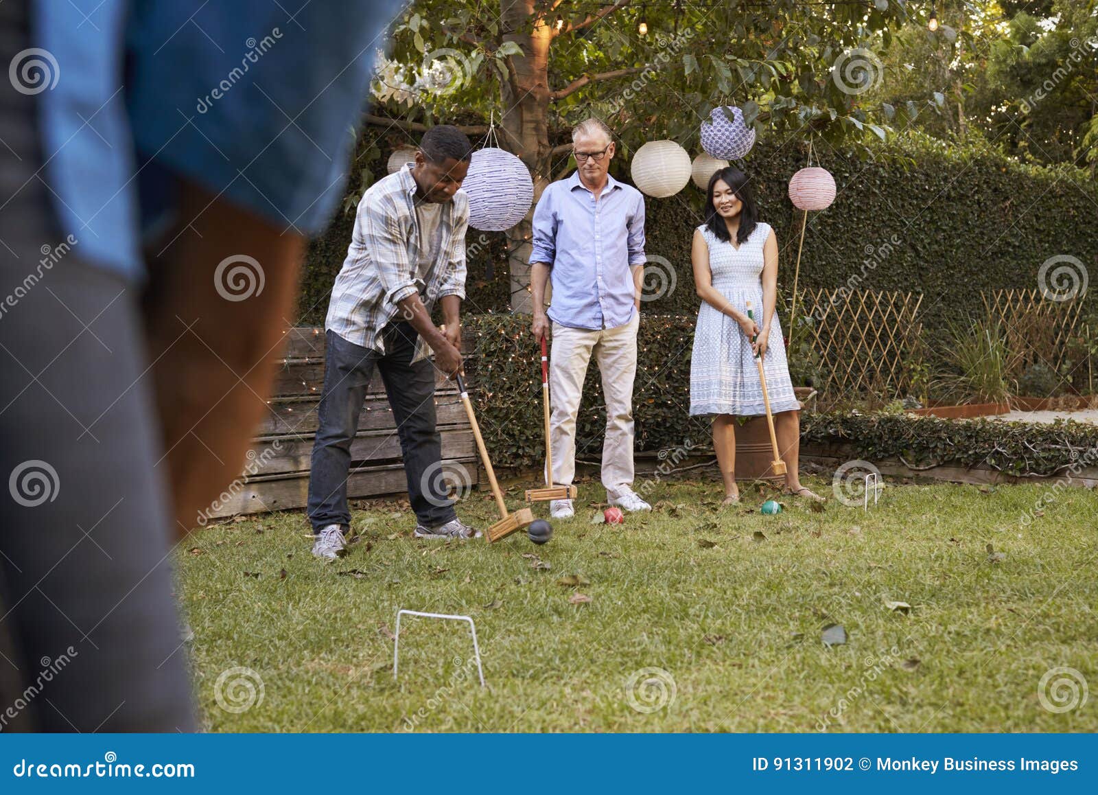 Group of Mature Friends Playing Croquet in Backyard Together Stock