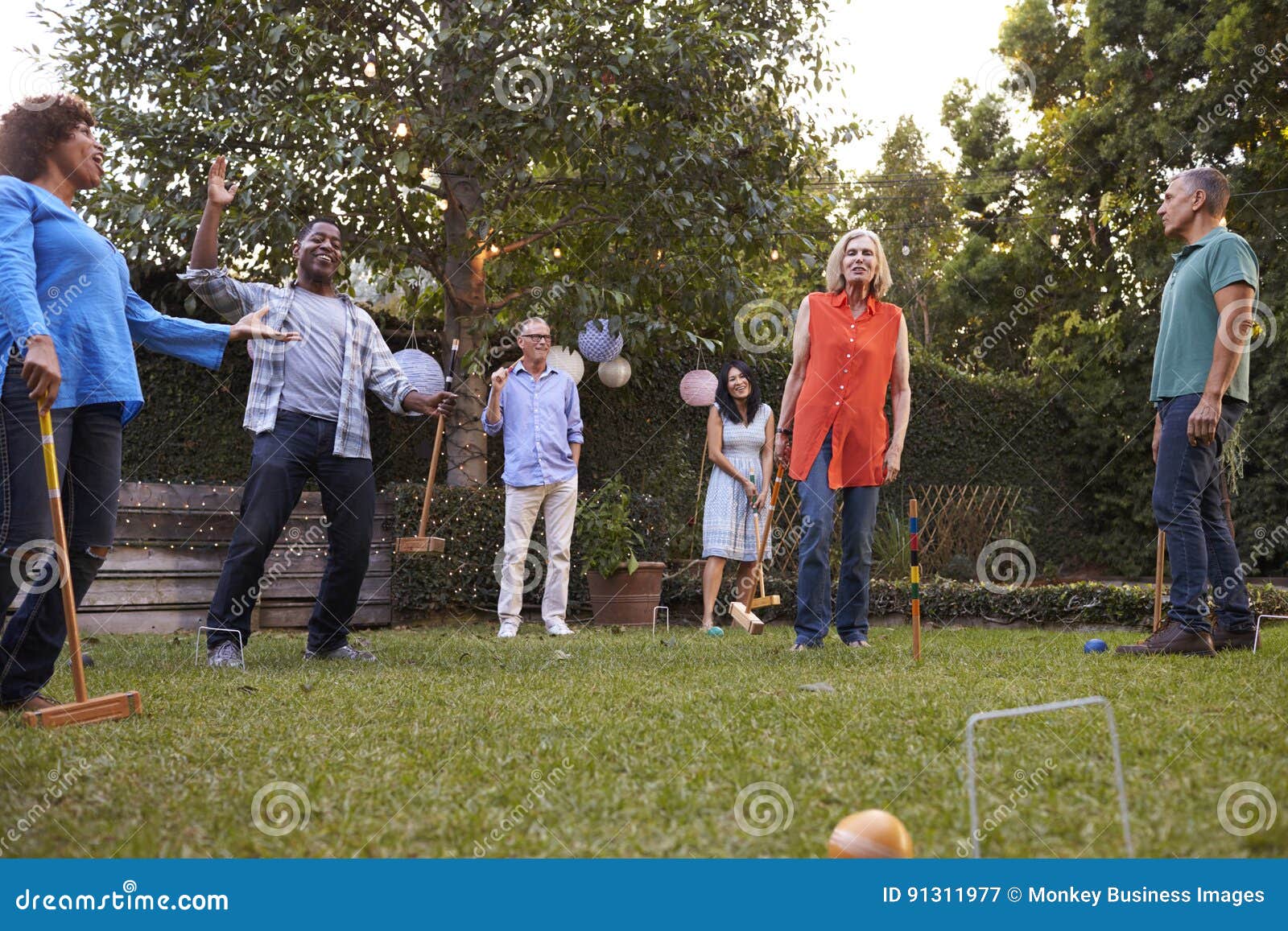 Group of Mature Friends Playing Croquet in Backyard Together Stock