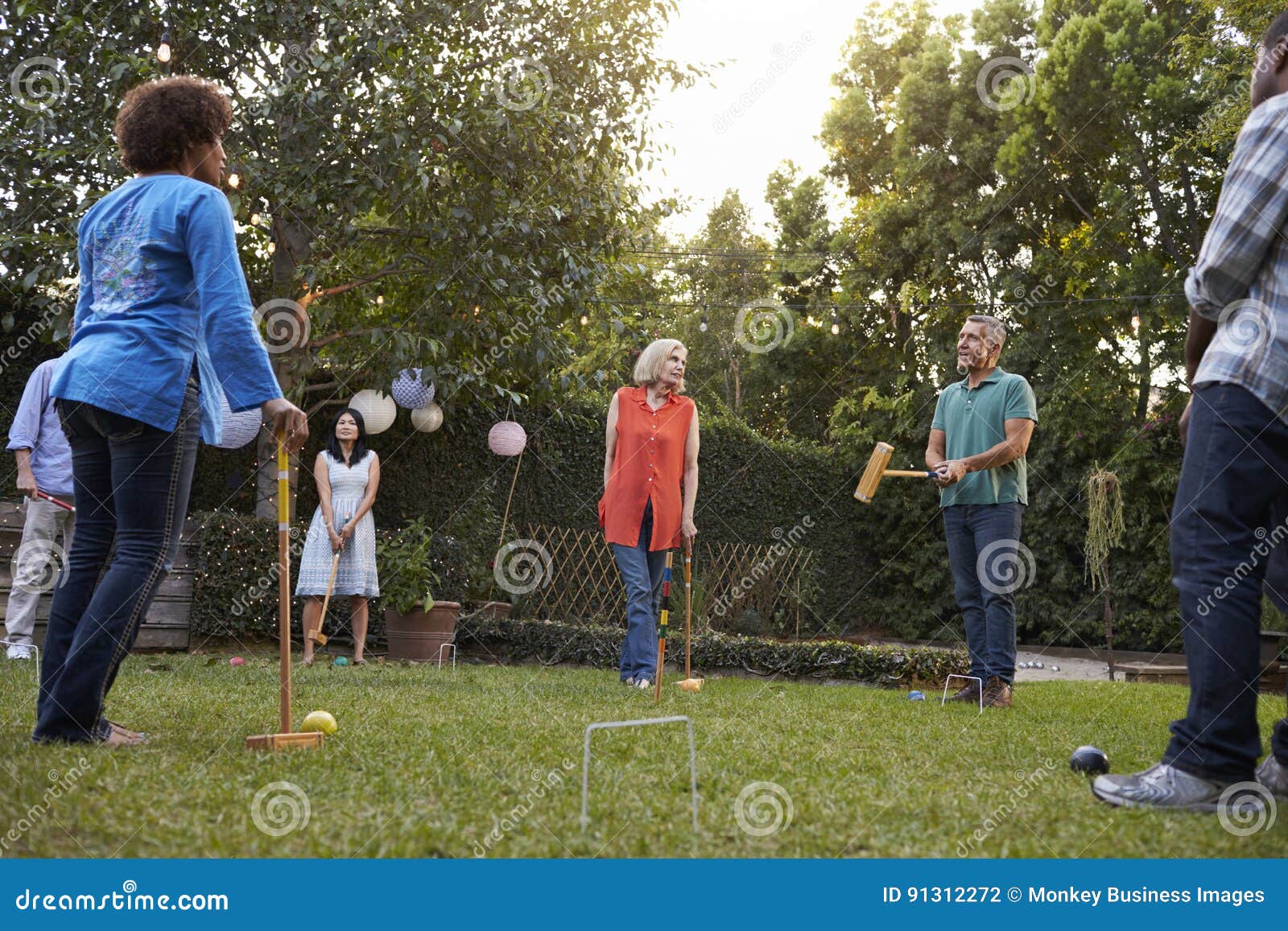 Group of Mature Friends Playing Croquet in Backyard Together Stock
