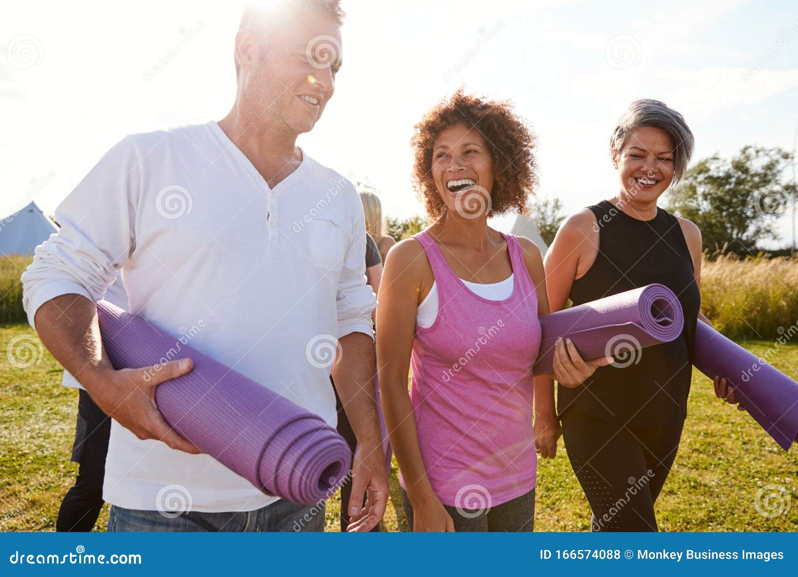 group of mature men and women with exercise mats at end of outdoor yoga class