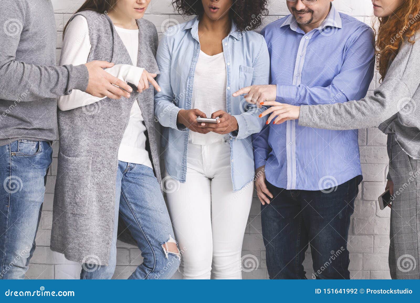 group of millennials reaching hands to cellphone