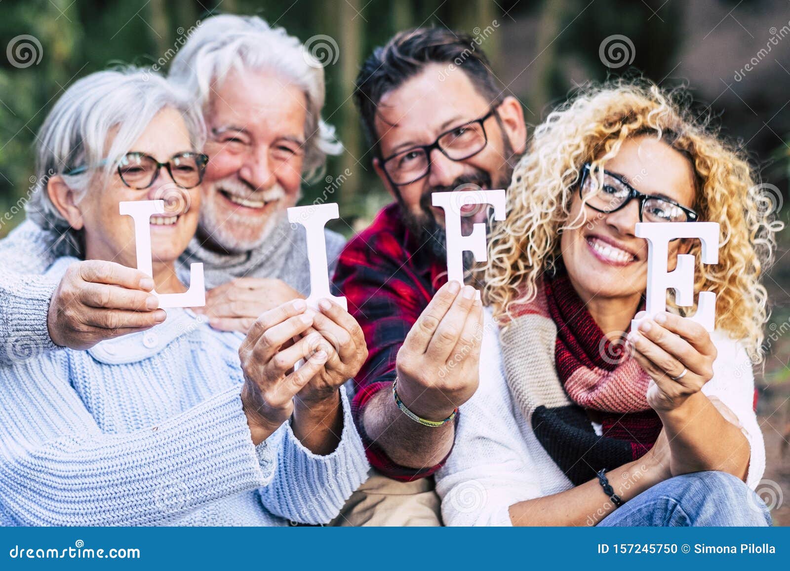 group of mixed ages generations people smiling and showing blocks letters with  life word -  happy lifestye enjoying the outdoor