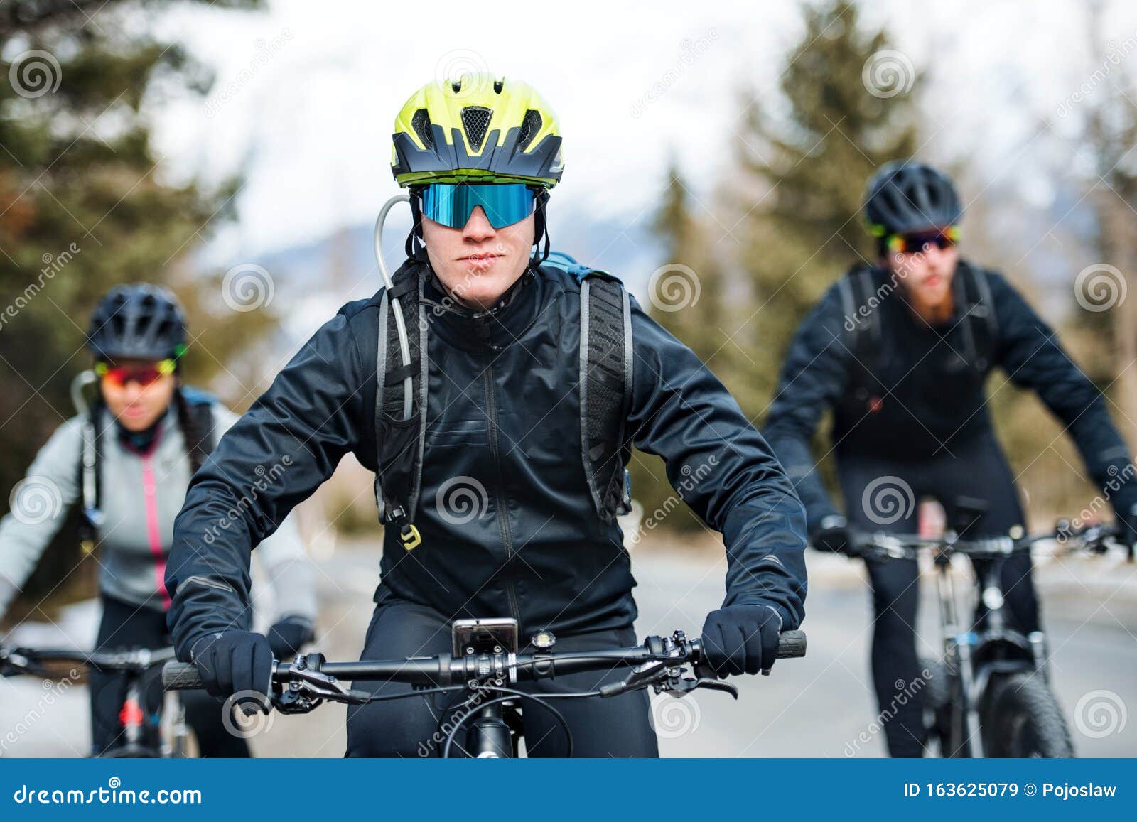 Group of Mountain Bikers Riding on Road Outdoors in Winter. Stock Image