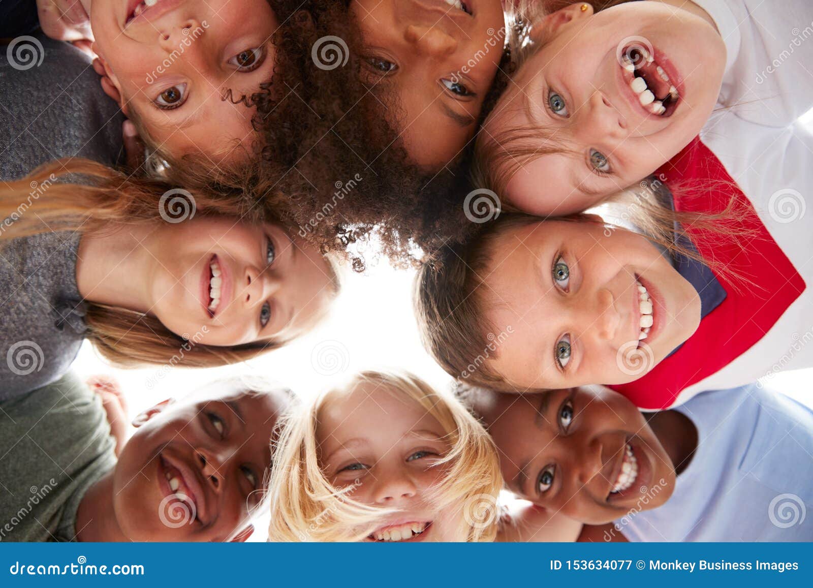 group of multi-cultural children with friends looking down into camera
