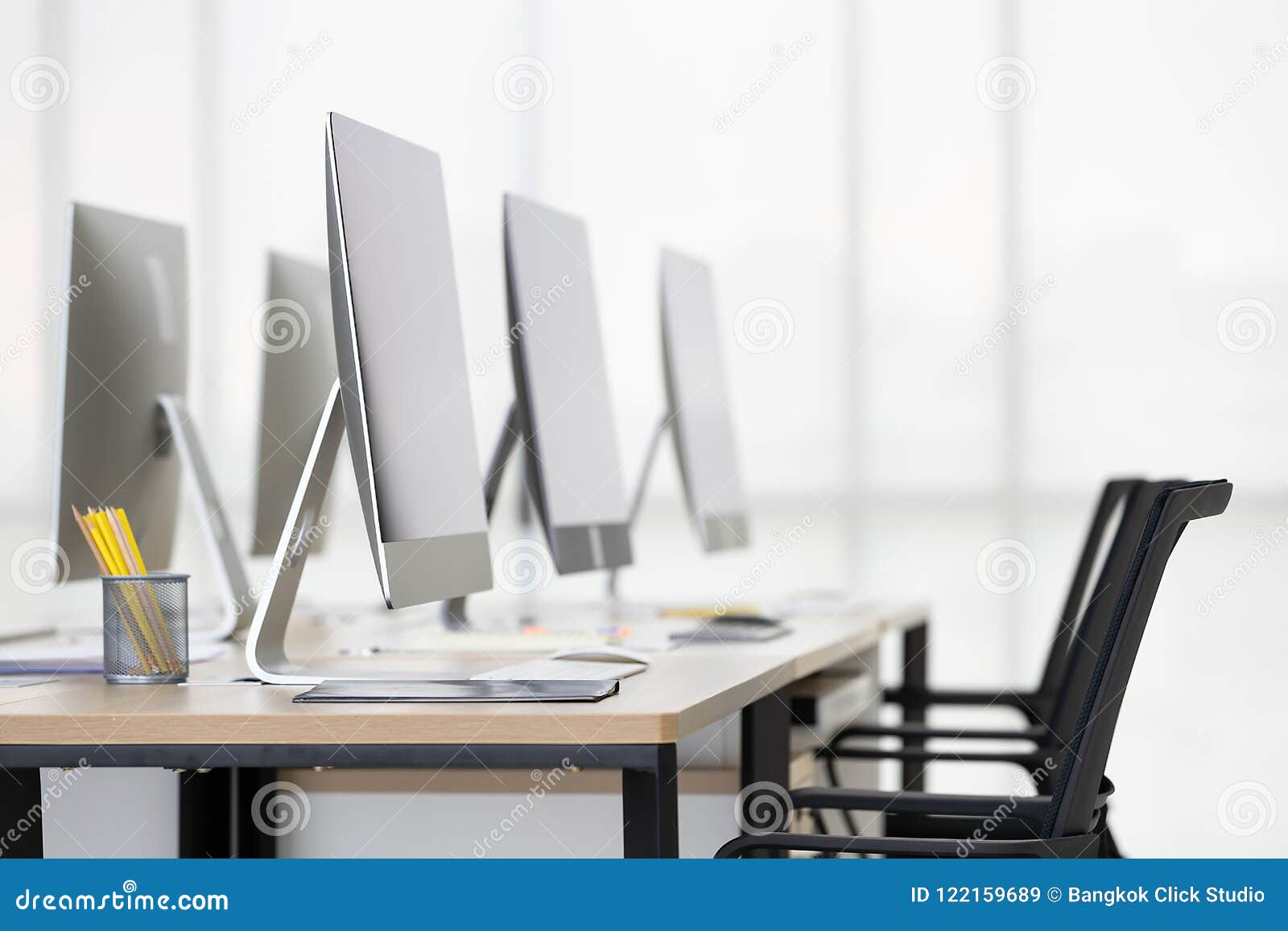 Group Of New Clean Computers On Desk In Modern Office With Windows