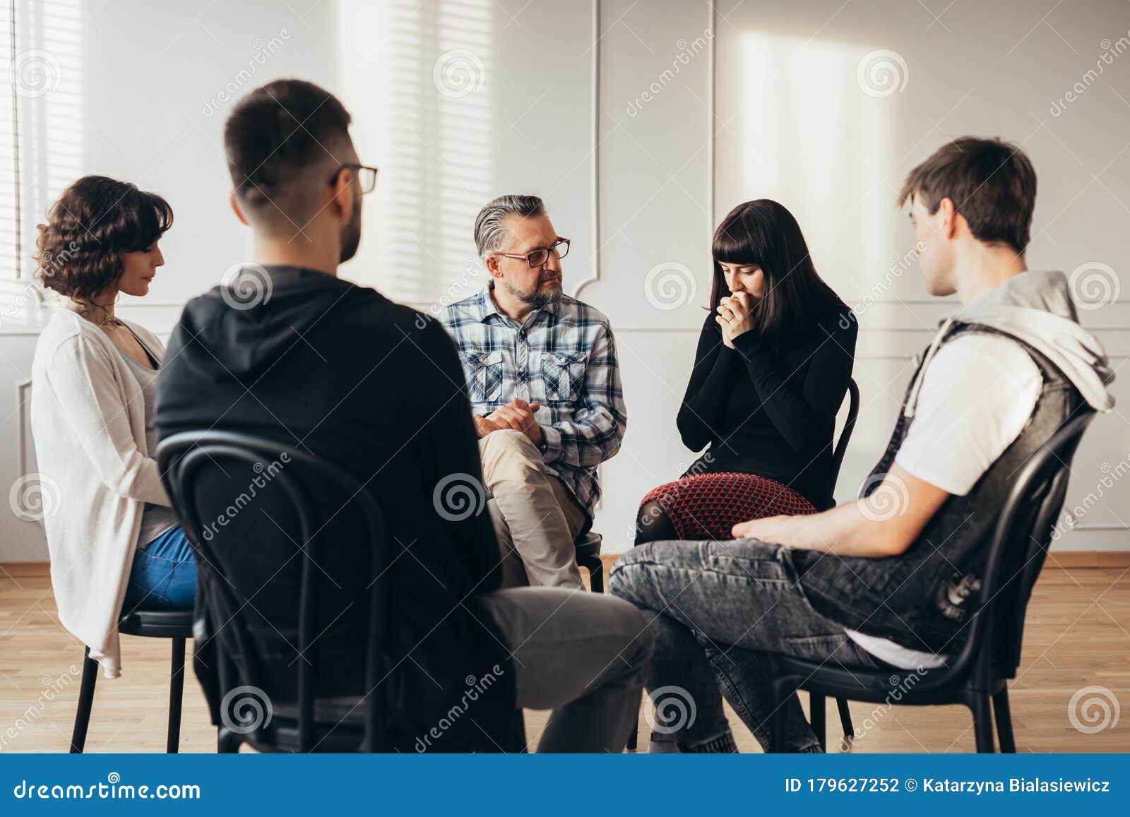 group of people of different ages sits in a circle during a meeting with a professional therapist