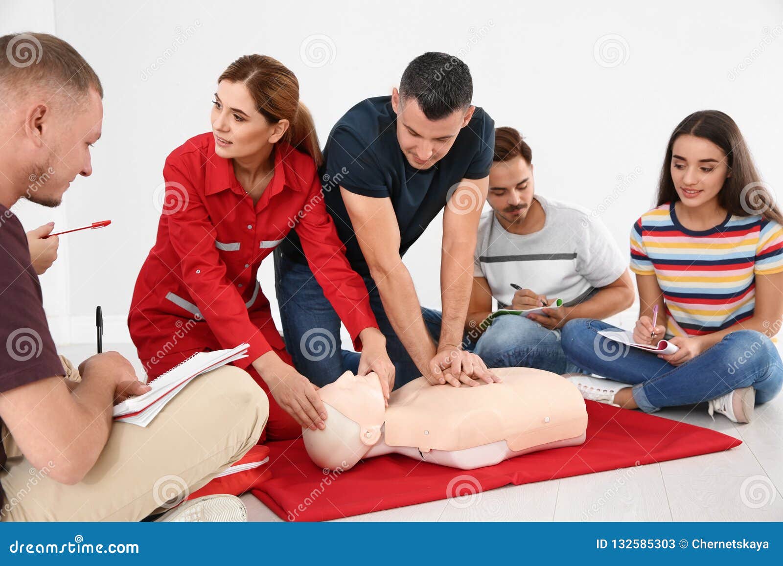 Group of People with Instructor Practicing CPR on Mannequin at First