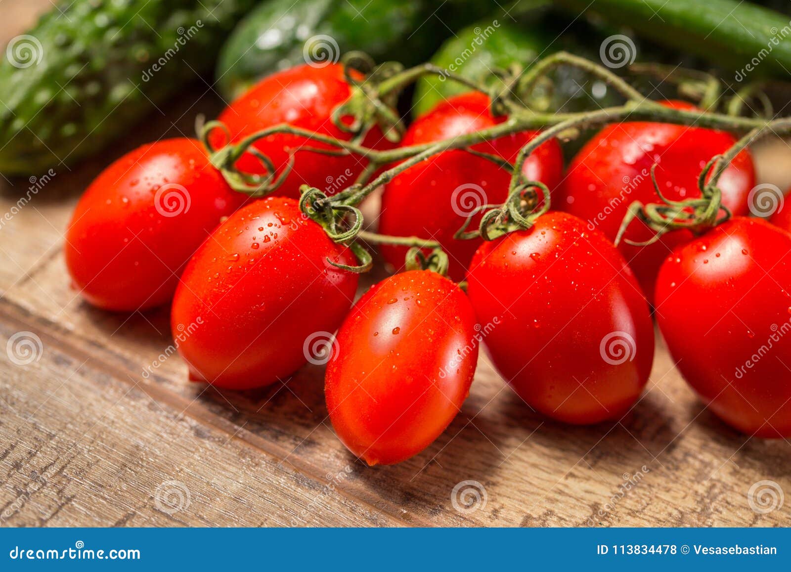 group of plum roma tomatoes ripe on a vine, on a wooden table