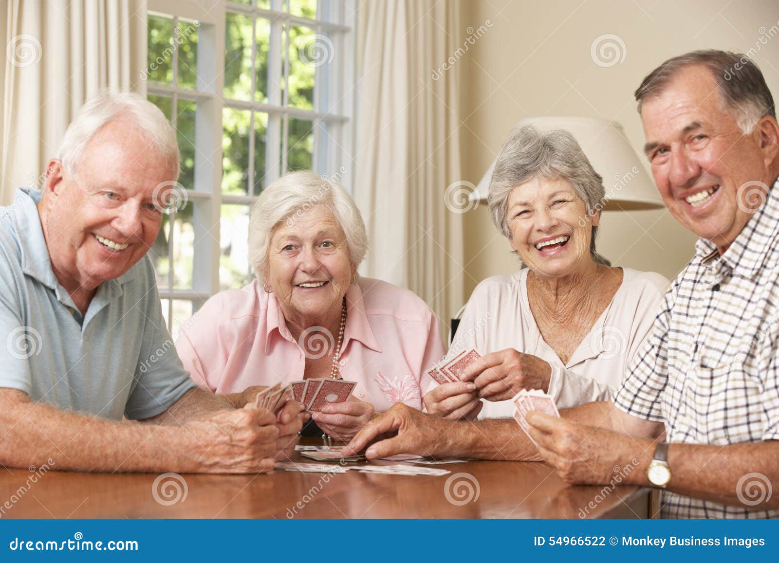 Group of Senior Couples Enjoying Game of Cards at Home Stock Photo