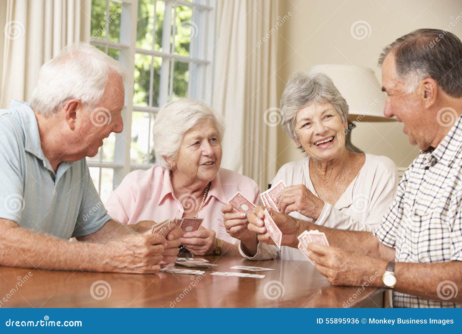 Group of Senior Couples Enjoying Game of Cards at Home Stock Photo