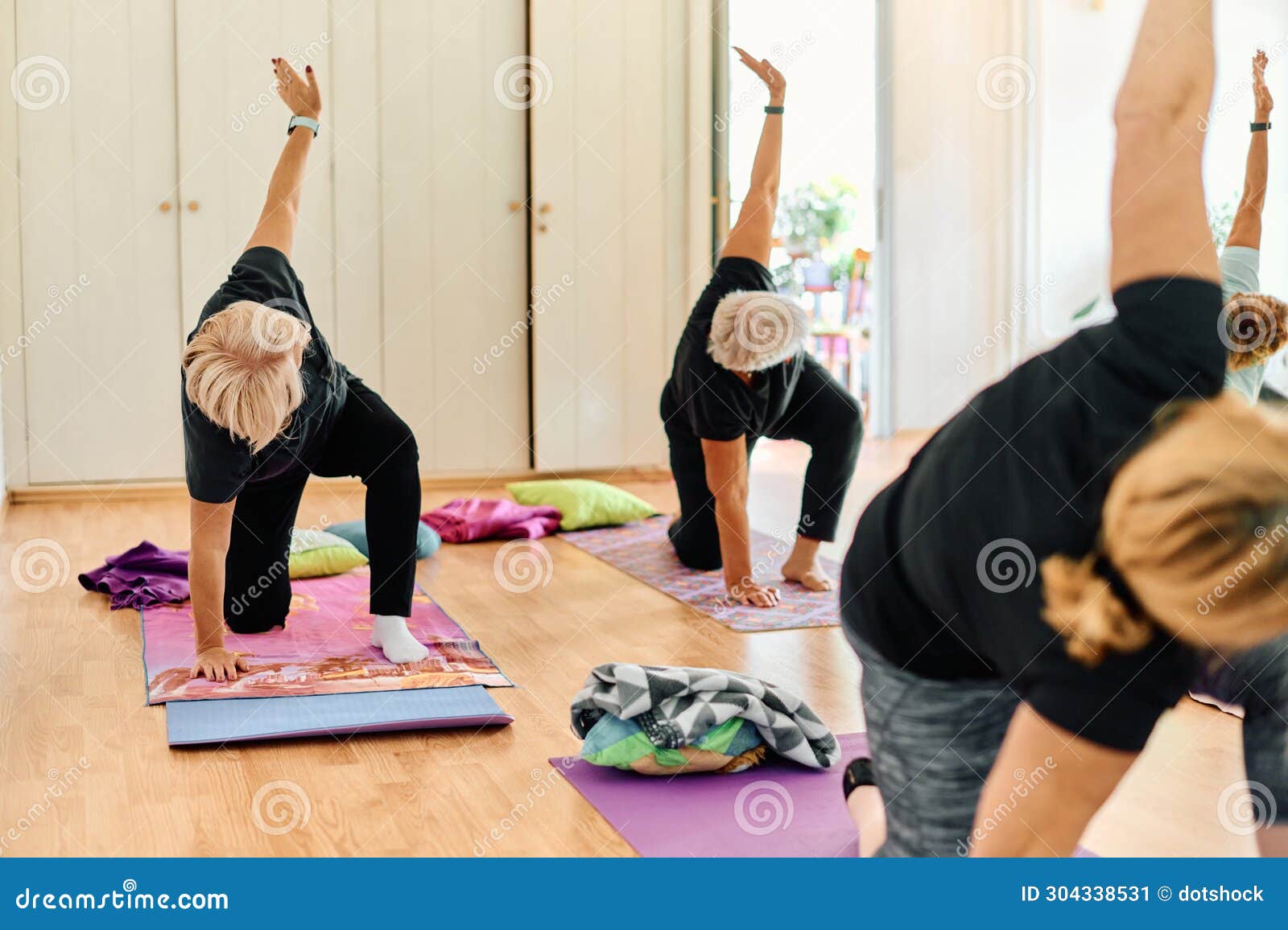 A Group of Senior Women Engage in Various Yoga Exercises, Including ...