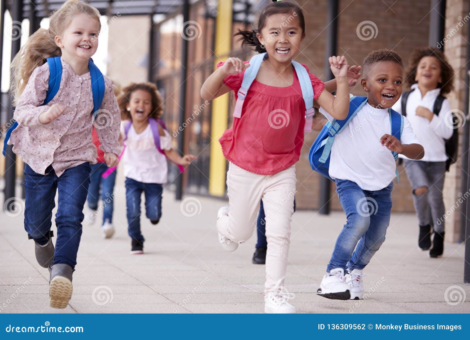 A Group of Smiling Multi-ethnic School Kids Running in a Walkway