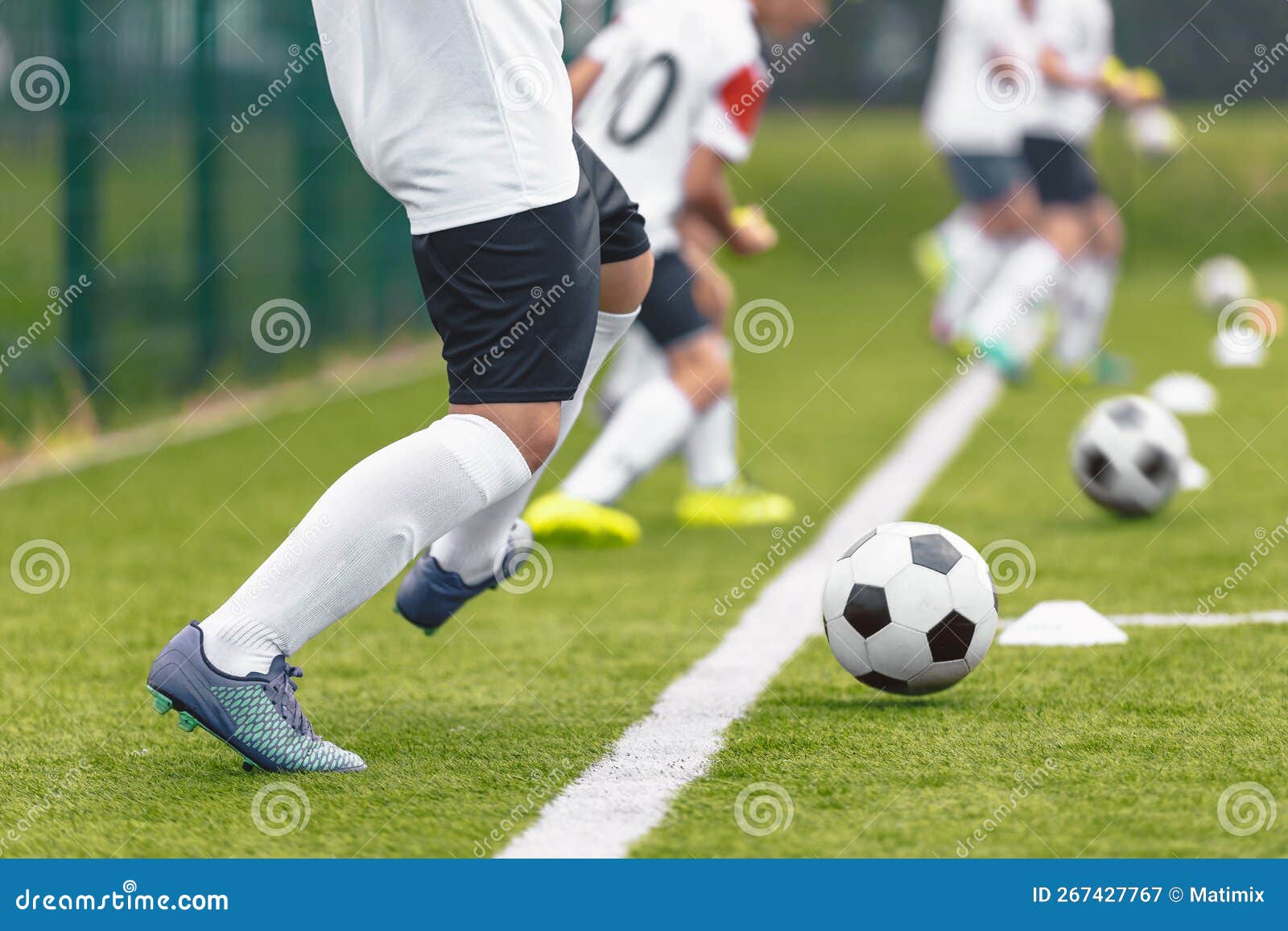 Group of Soccer Players Kicking Balls on Training Drill Along Sideline