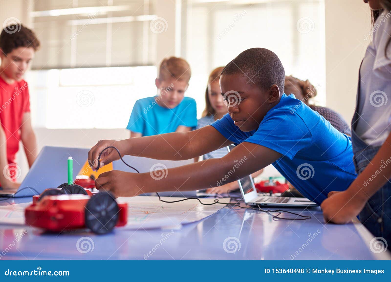 Group of students in a school computer coding class learning to program a robot vehicle.