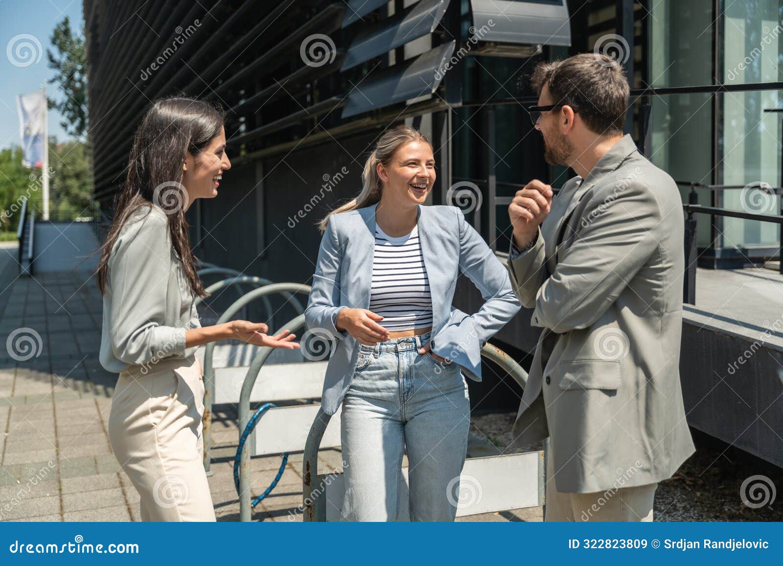 group of successful young business people, leaders in marketing and motivation, stand in front of office building and consult