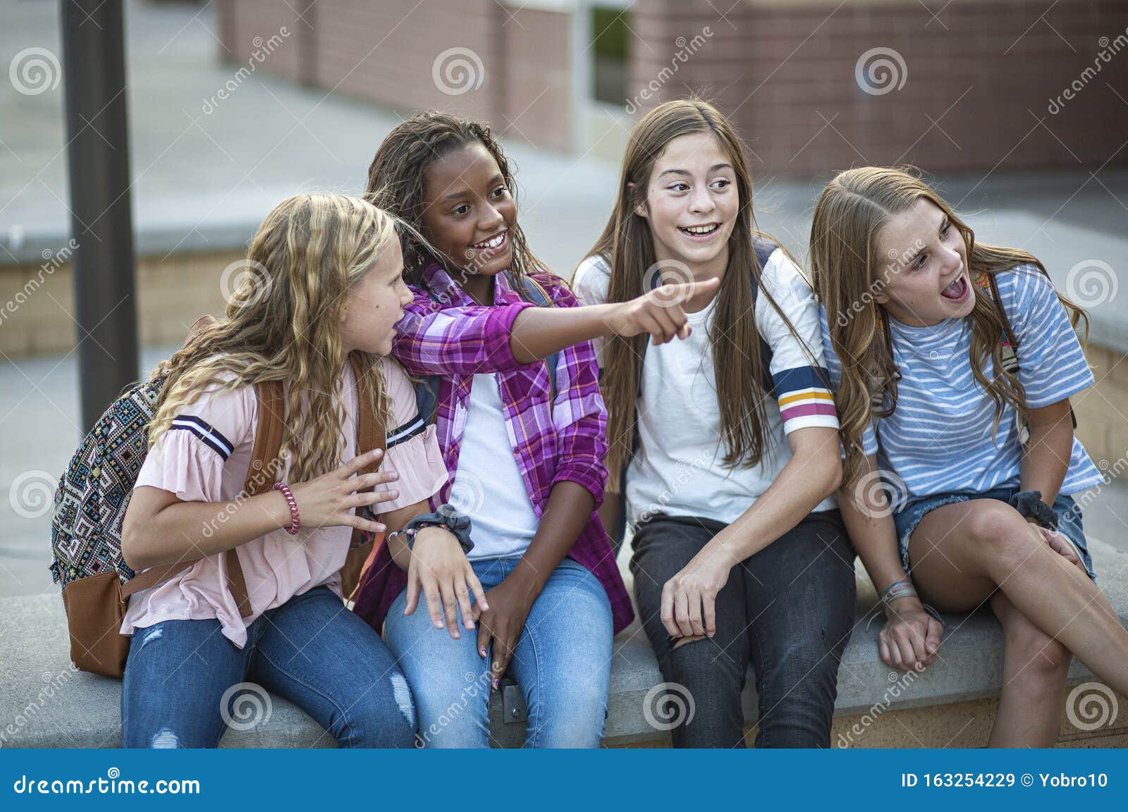 Group of Teenage Girls Laughing and Talking Together at School Stock