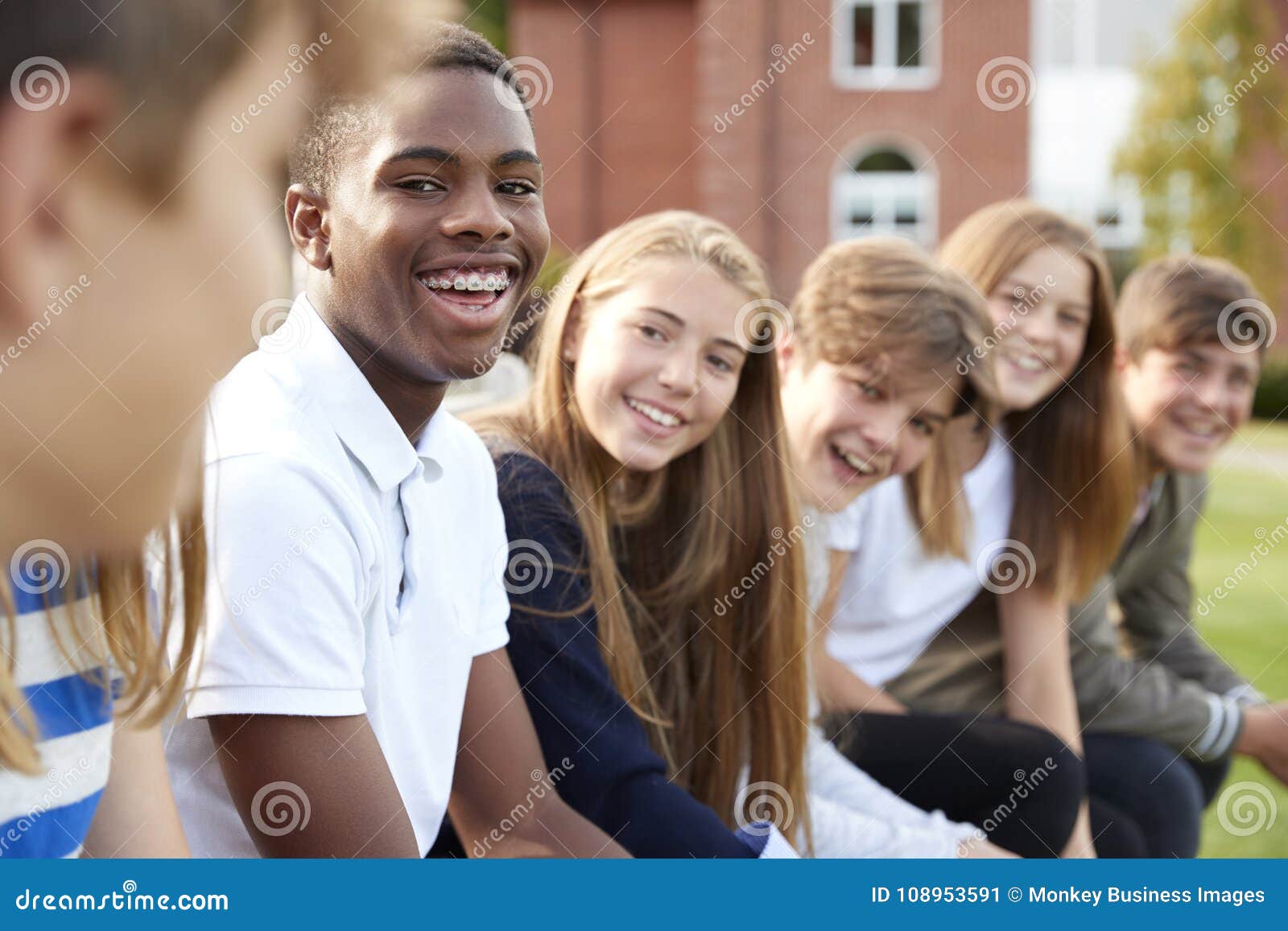 group of teenage students sitting outside school buildings