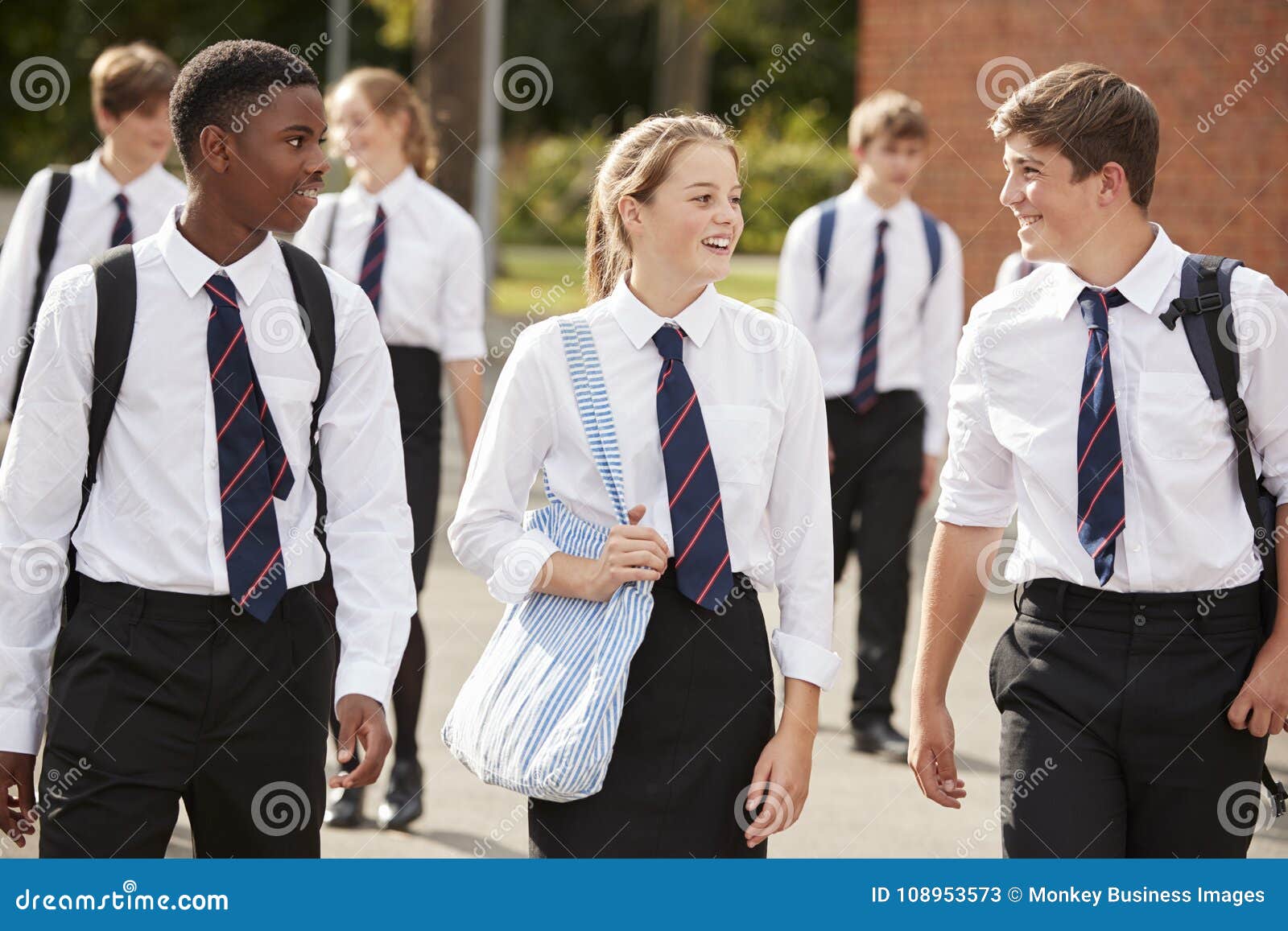 group of teenage students in uniform outside school buildings