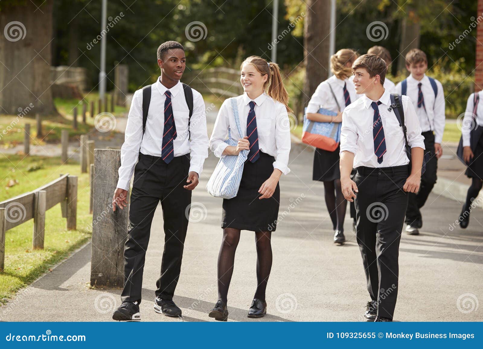 group of teenage students in uniform outside school buildings