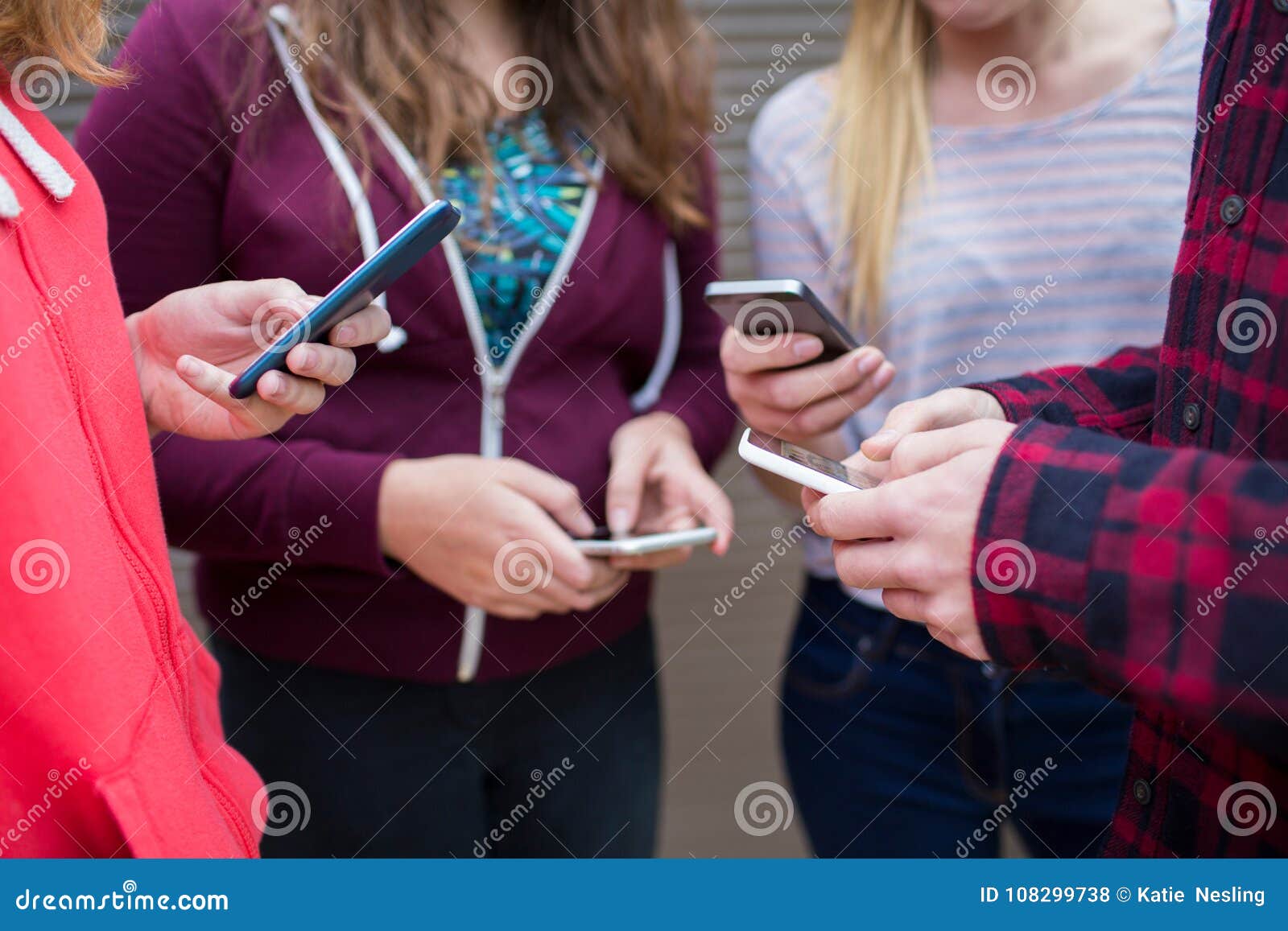 group of teenagers sharing text message on mobile phones