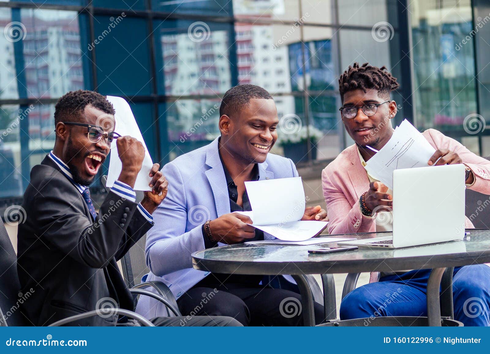 a group of their three successful african american businessmen in a stylish suit sit at the table and work with a laptop