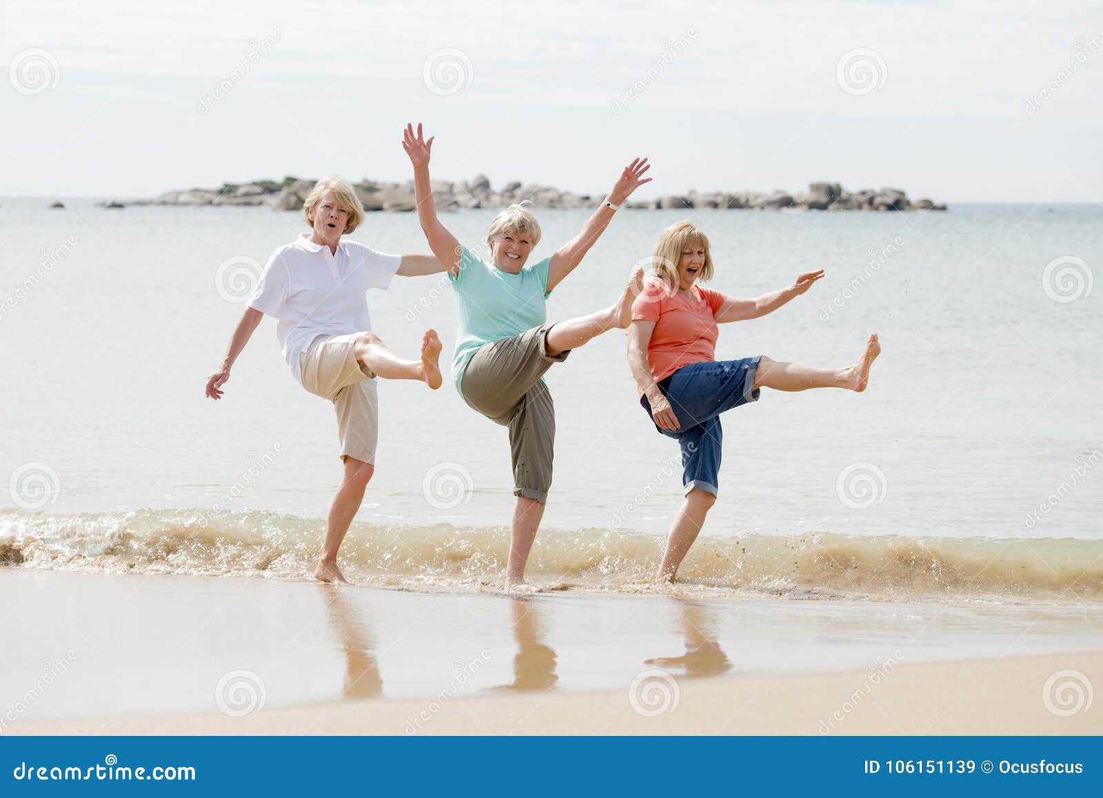 group of three senior mature retired women on their 60s having fun enjoying together happy walking on the beach smiling playful