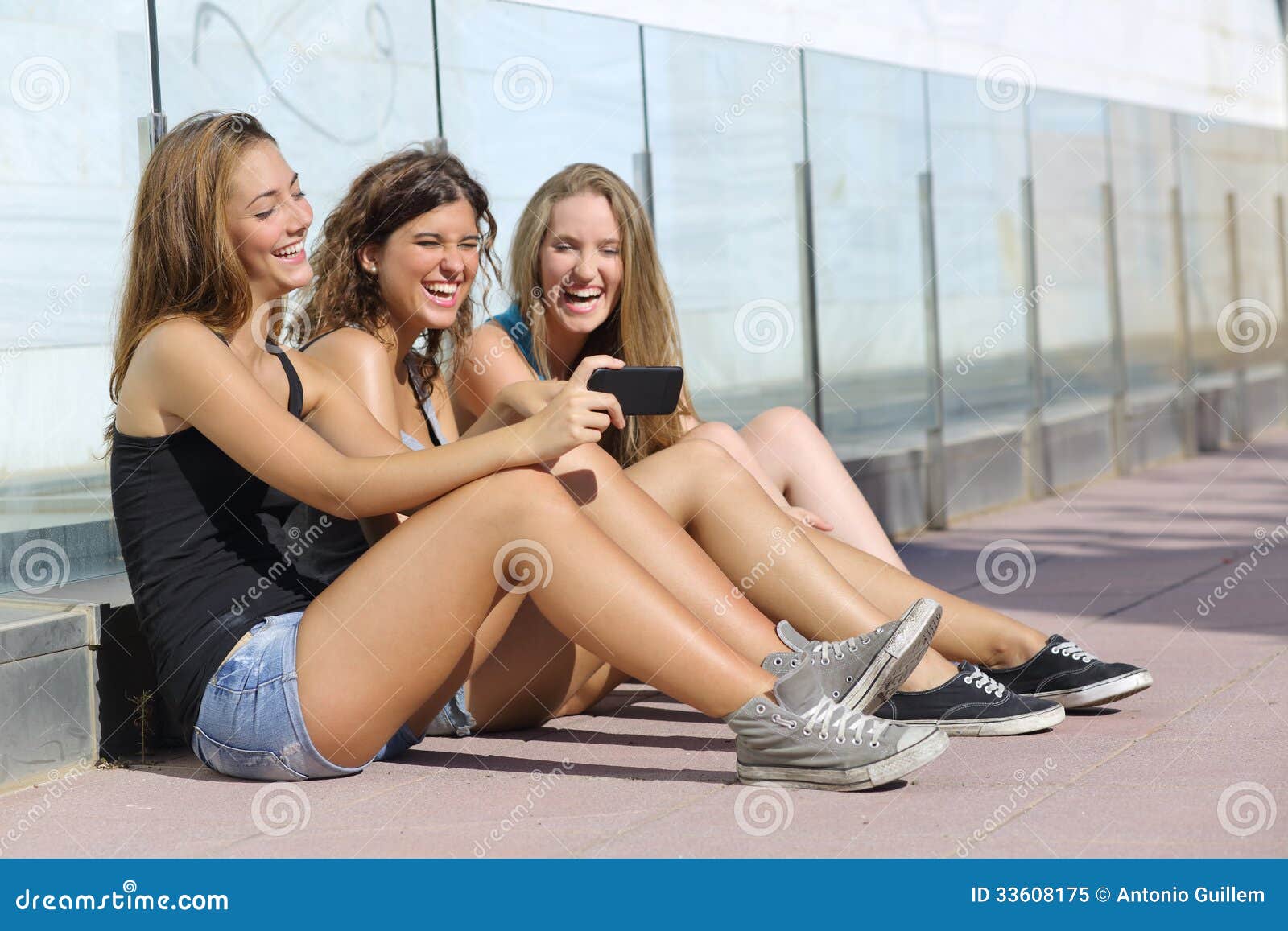 group of three teenager girls laughing while watching the smart phone