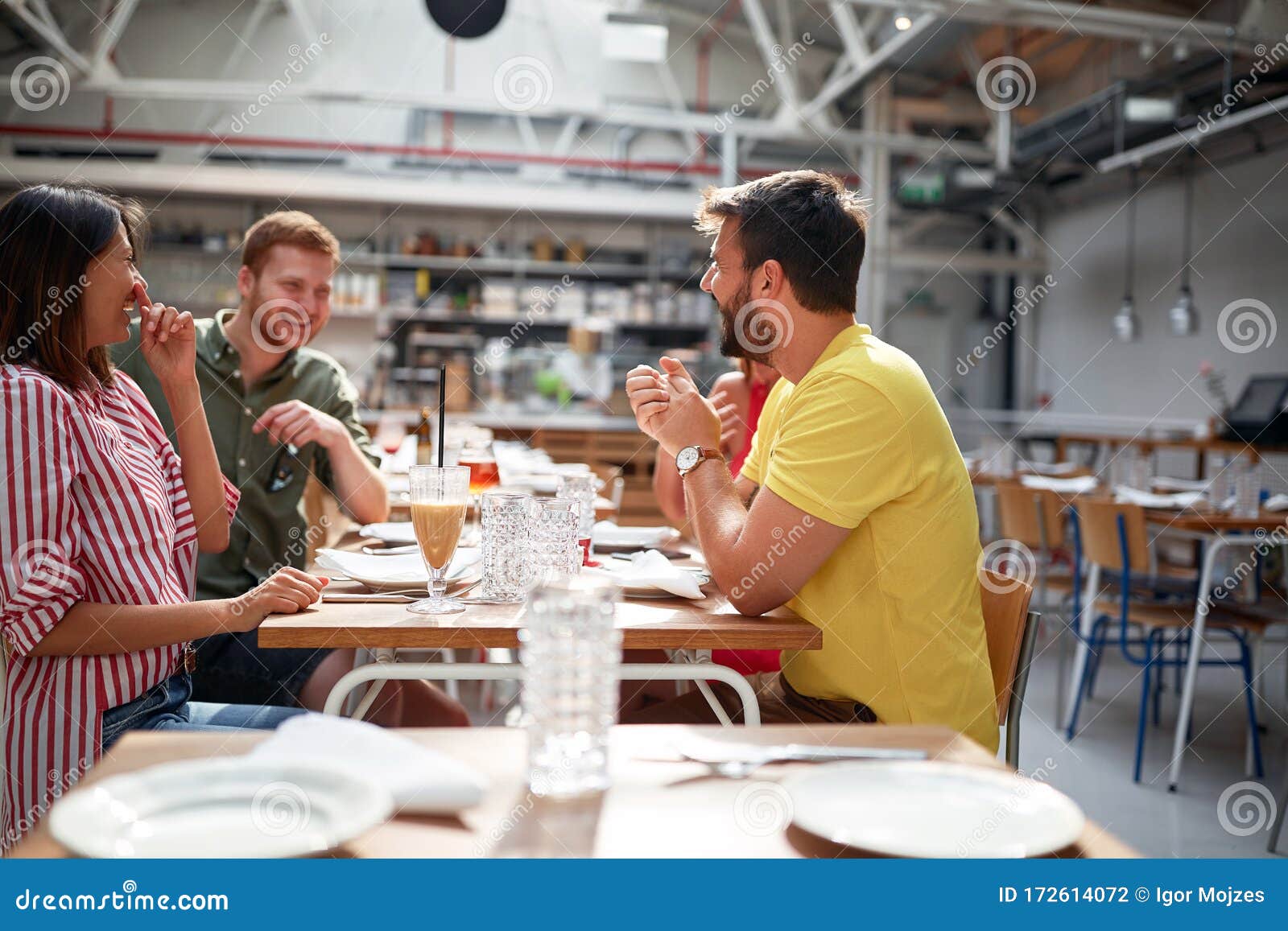 Group of Young Adults Talking and Smiling in Restaurant Stock Photo
