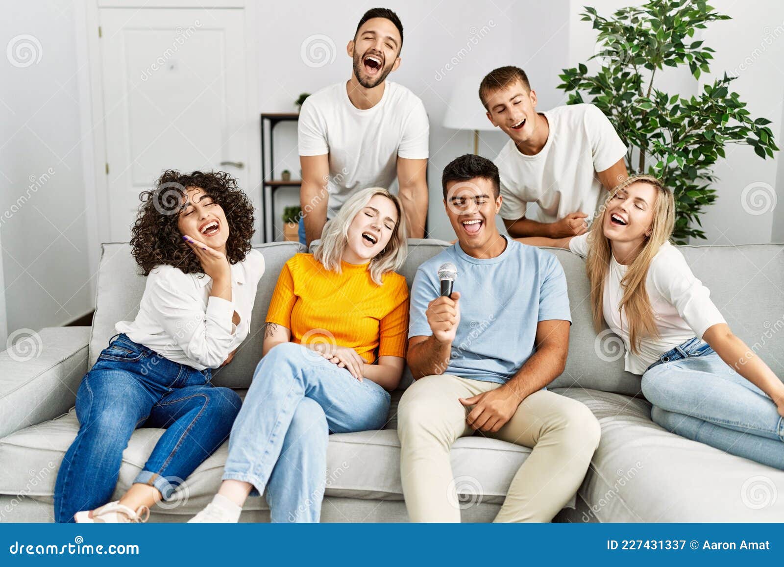 Group of Young Friends Having Party Singing Song Using Microphone at