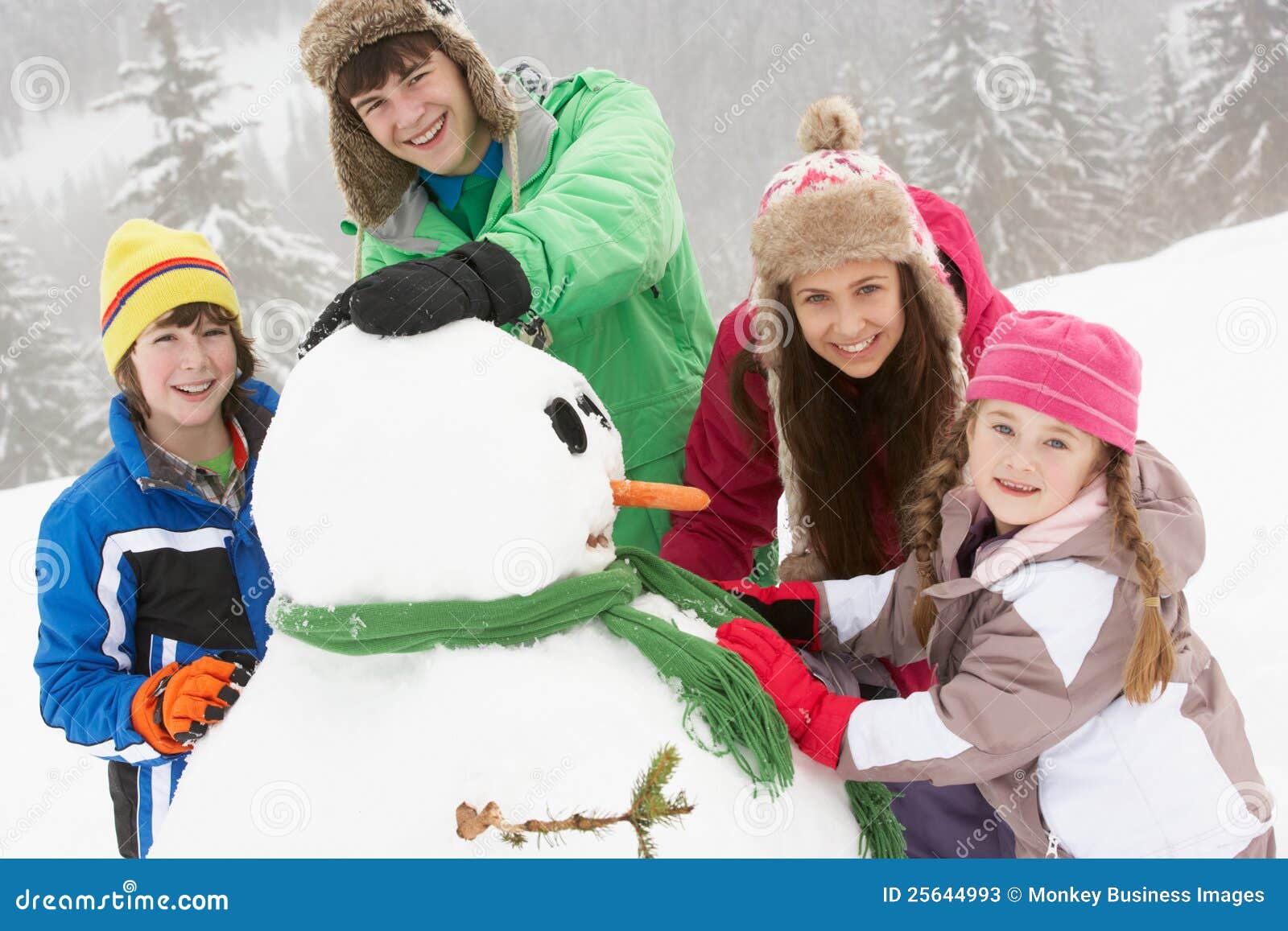 Grupo de crianças que constroem o boneco de neve no feriado do esqui nas montanhas