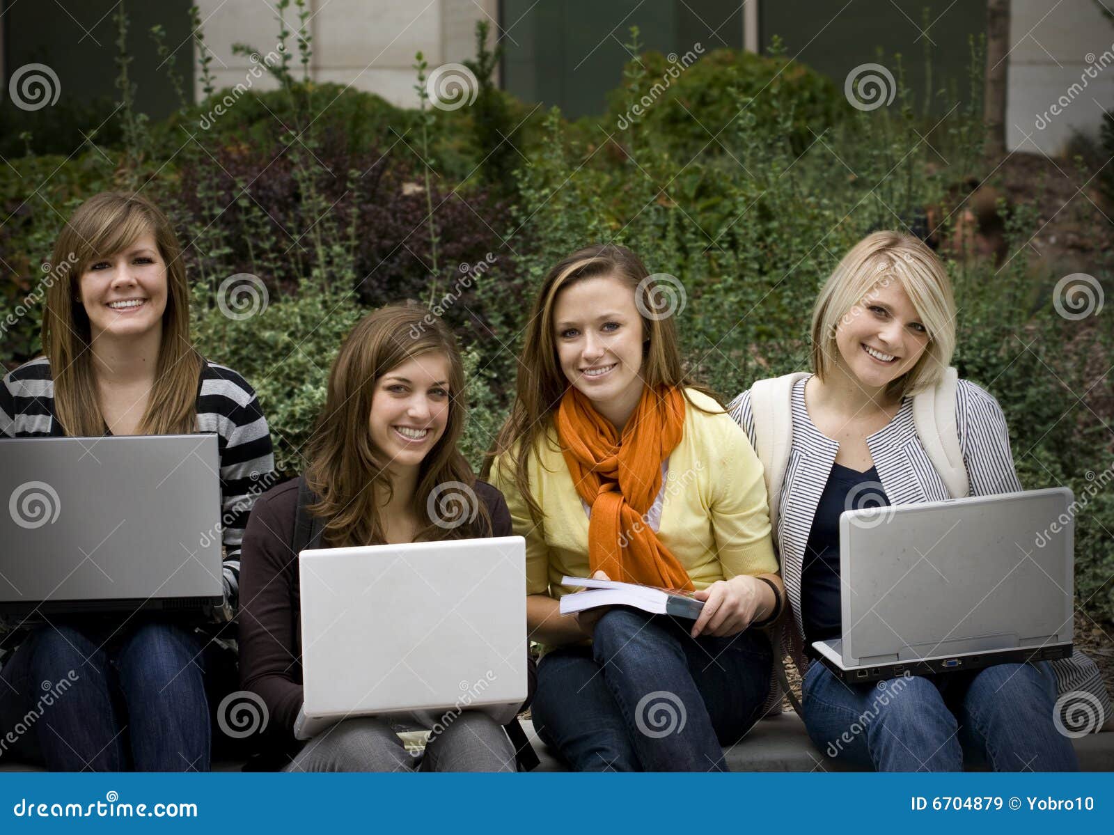 Grupo de estudiantes universitarios. Un grupo de estudio de estudiantes universitarios de sexo femenino atractivos que sonríen mientras que estudia en sus ordenadores portátiles