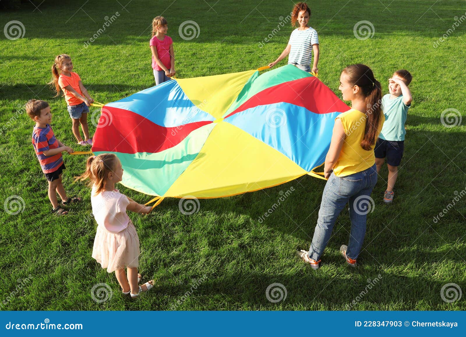 Grupo De Niños Y Profesores Jugando Con Paracaídas En Un Parque Infantil  Arco Iris Sobre Césped Verde. Actividad De Campamento De Imagen de archivo  - Imagen de campo, feliz: 228347903