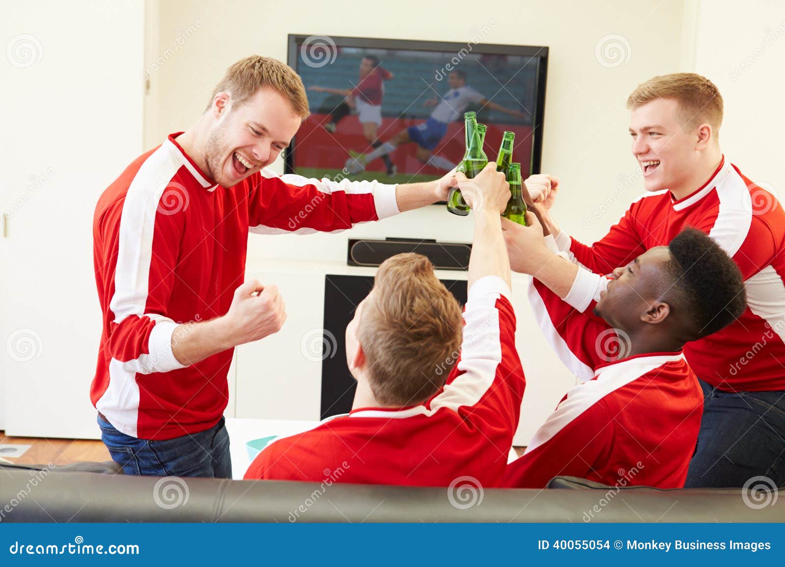 Gruppe Sport-Fans, die im Fernsehen Spiel zu Hause aufpassen. Gruppe Sport-Fans, die im Fernsehen Spiel, zu Hause aufpassen Flasche Biere zu halten machen einen Toast