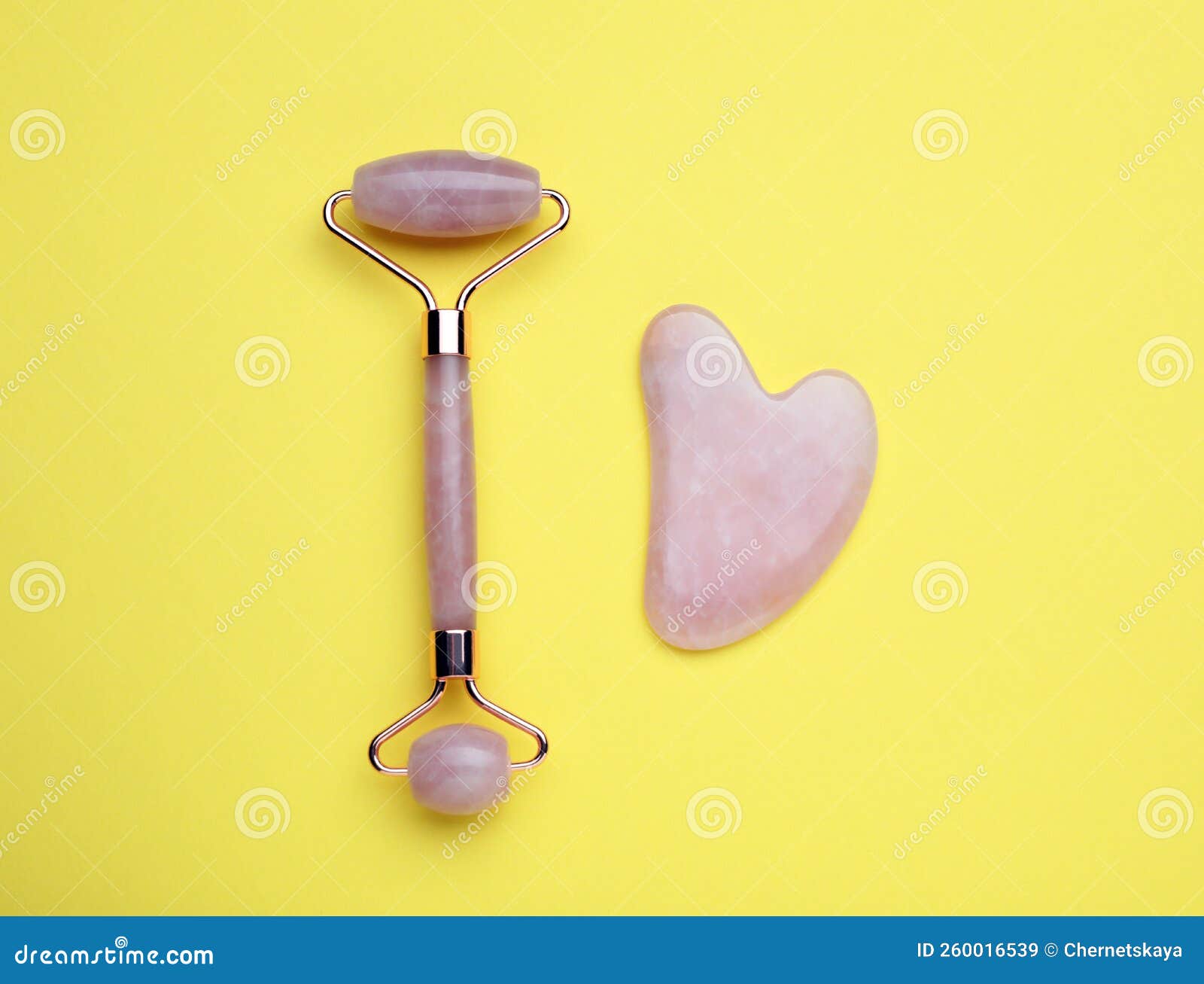 Gua Sha Stone and Face Roller on Yellow Background, Flat Lay Stock