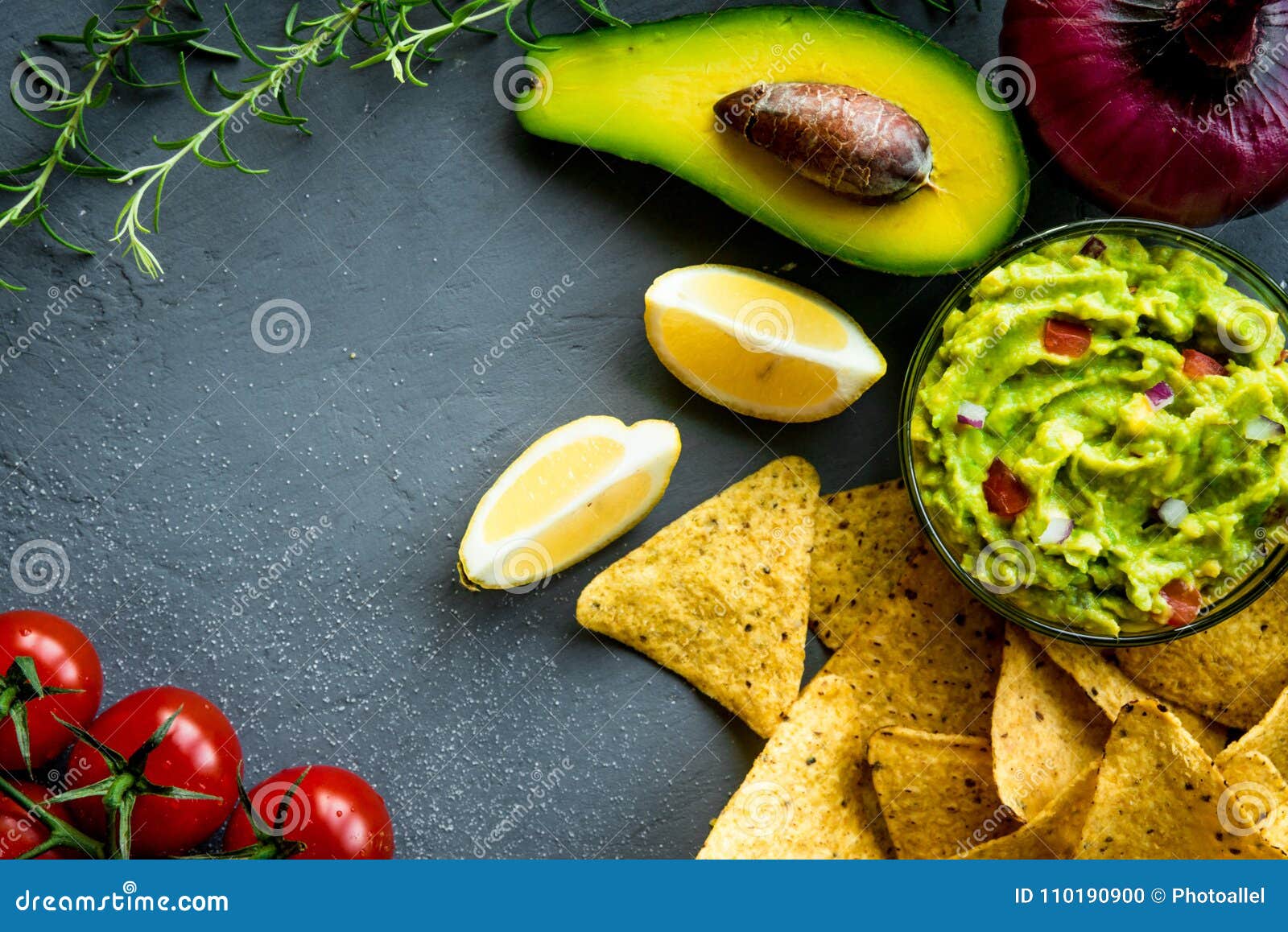 Guacamole Bowl with Ingredients and Tortilla Chips on a Stone Table