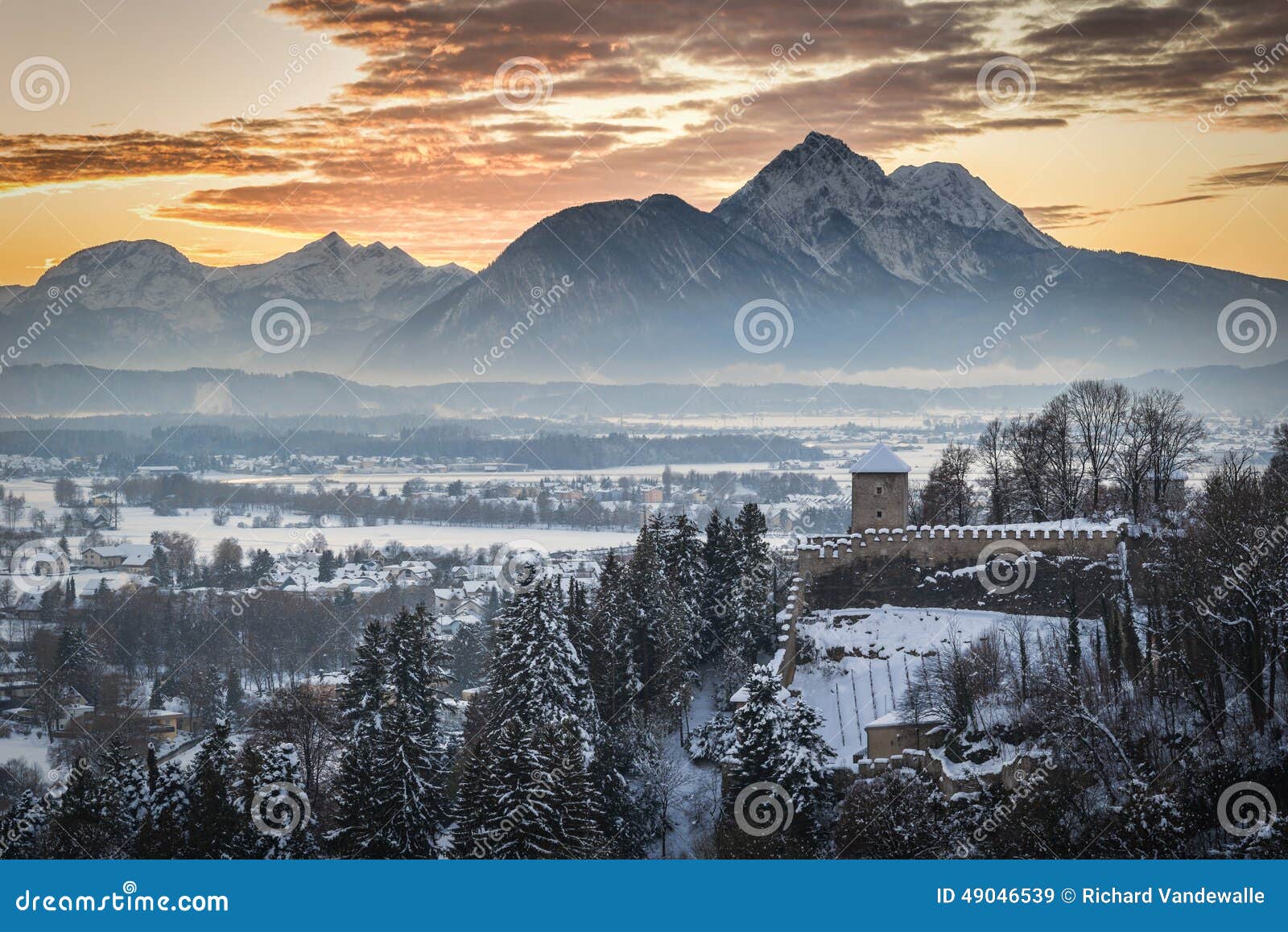 Medieval guard tower with snow covered mountain in background at sunset.