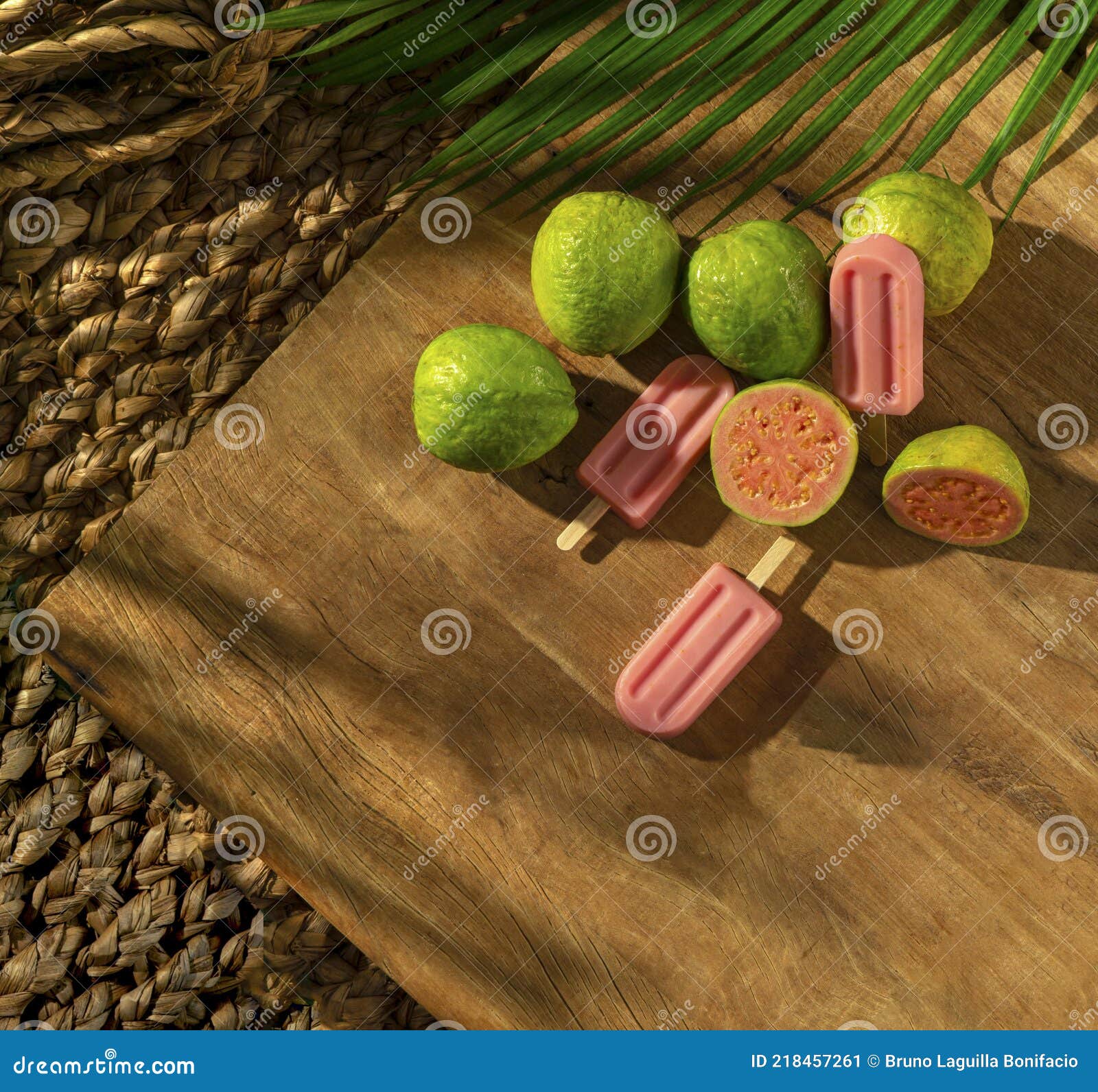guava popsicle with grava fruits on a wood base, sunlight, palm leaf, top view