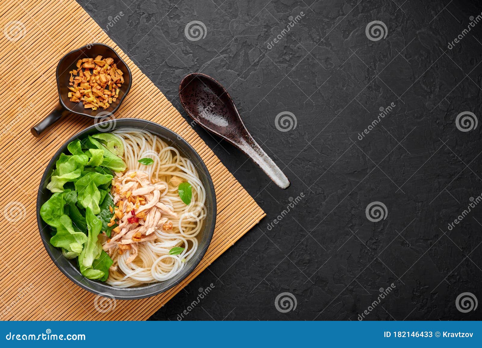 guay tiew gai cheek or thai chicken noodle soup in black bowl on dark slate backdrop. thai food
