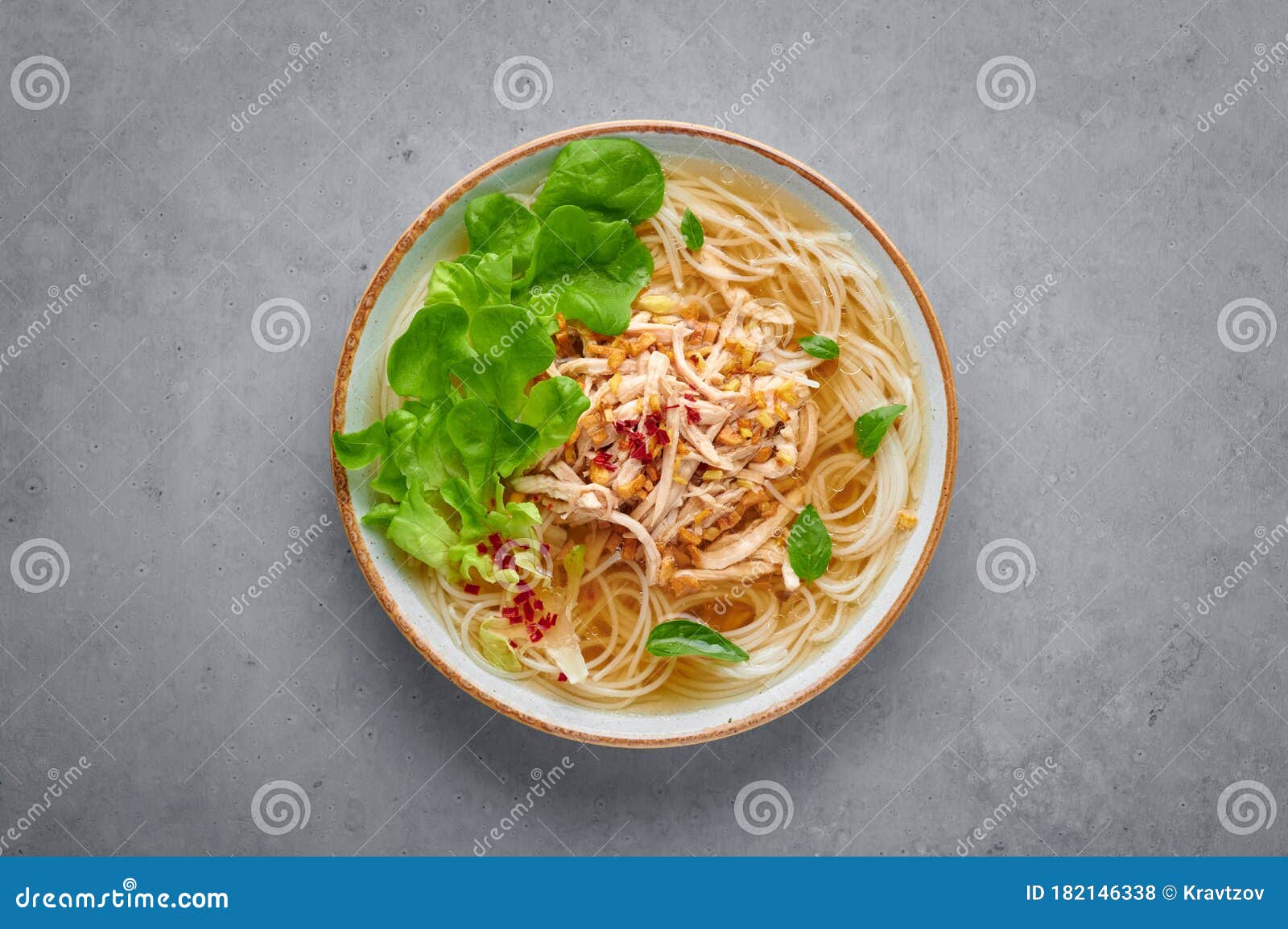 guay tiew gai cheek or thai chicken noodle soup in white bowl on gray concrete backdrop. thai food