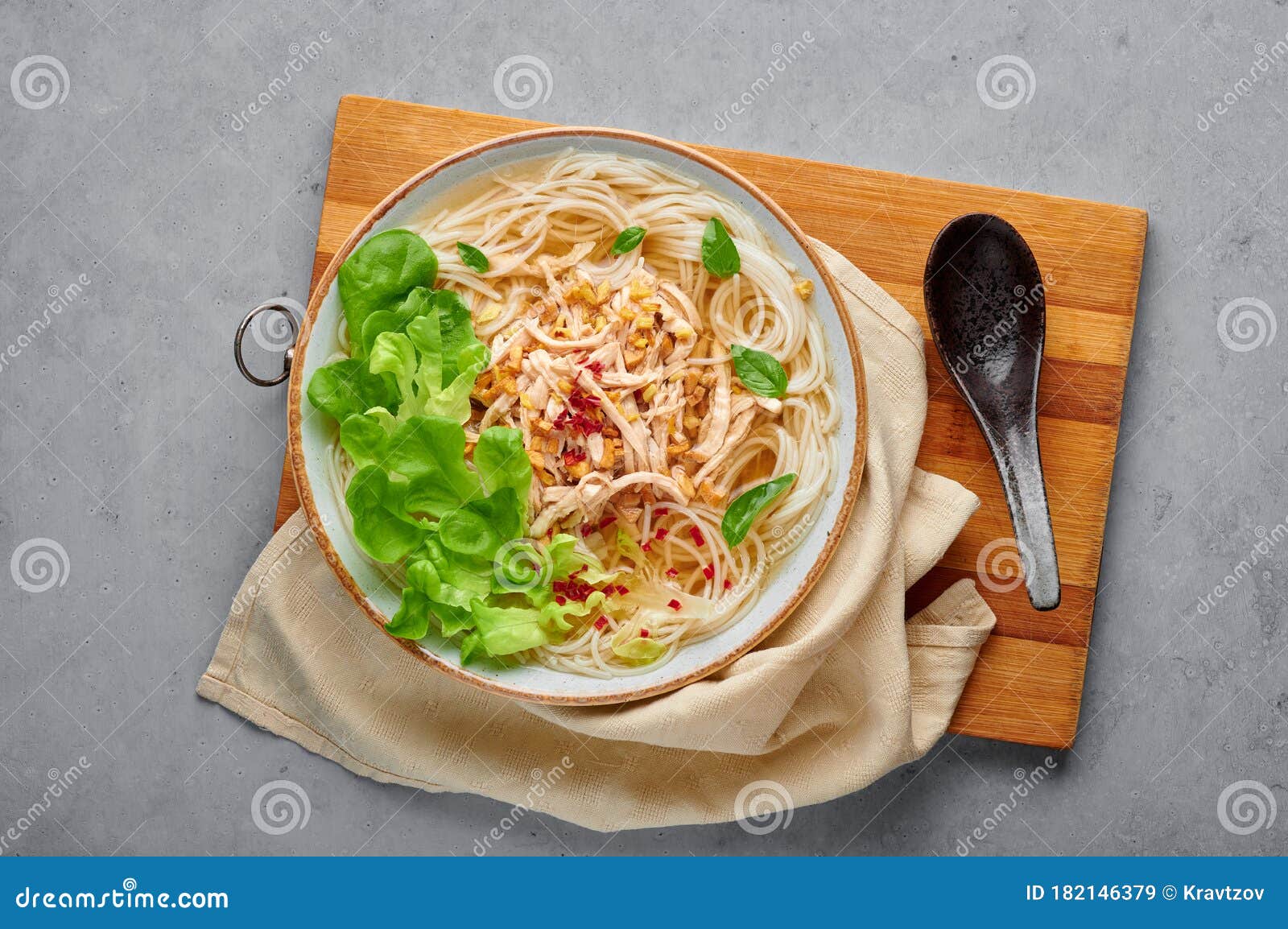 guay tiew gai cheek or thai chicken noodle soup in white bowl on gray concrete backdrop. thai food