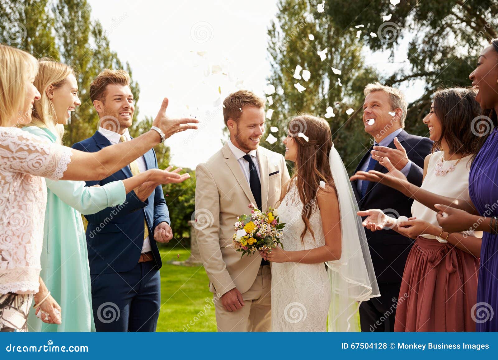 Guests Throwing Confetti Over Bride and Groom at Wedding Stock Photo