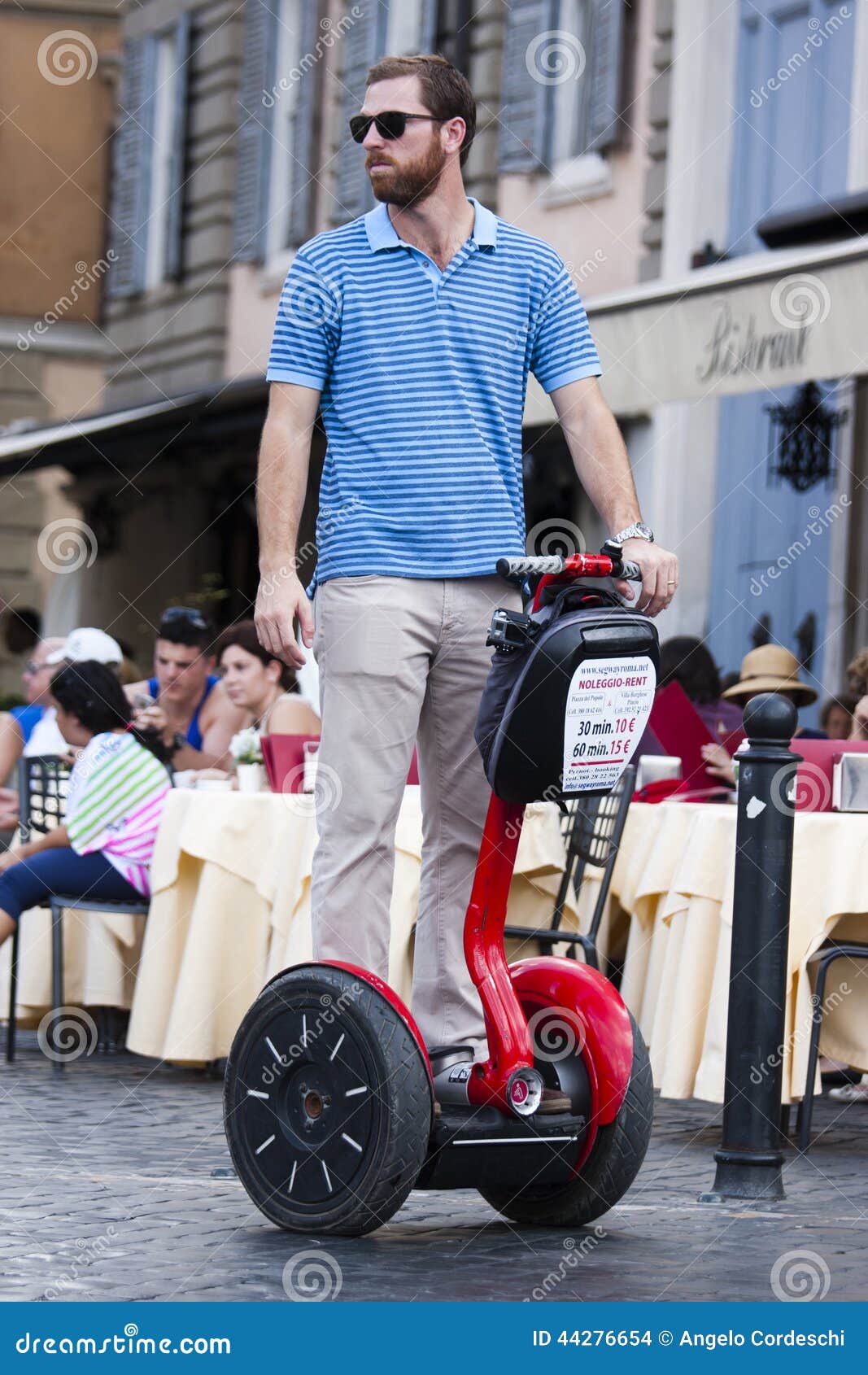 Guida dell'uomo segway. Uomo guidando segway in Piazza del Popolo in Roma)/dietro (dell'Italia lui, un ristorante/l'abbigliamento casual ed occhiali da sole d'uso