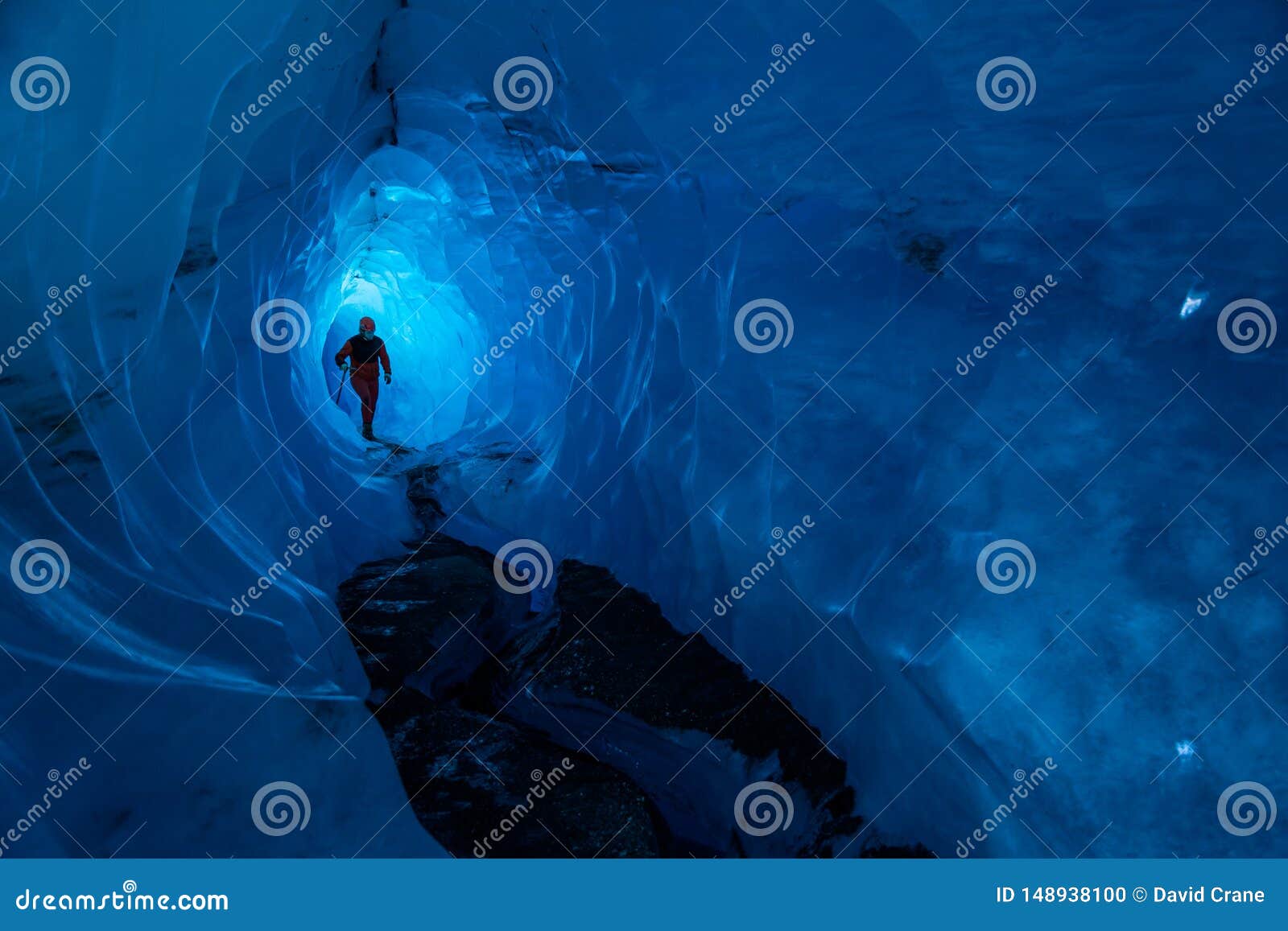 guide inside an ice cave on a glacier in alaska. glacier caves are rare on teh matanuska, but this one runs deep into the ice