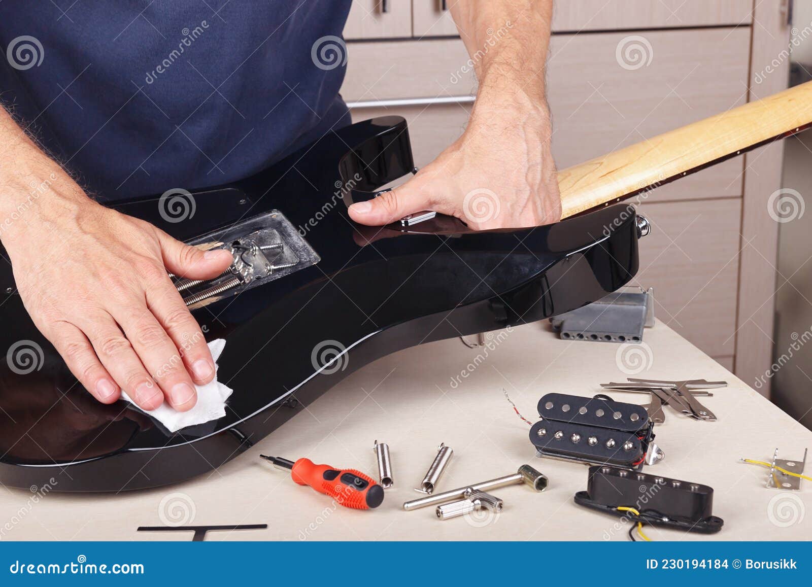 Guitar Repairer Wipes Surface of Modern Electric Guitar with Rag Stock