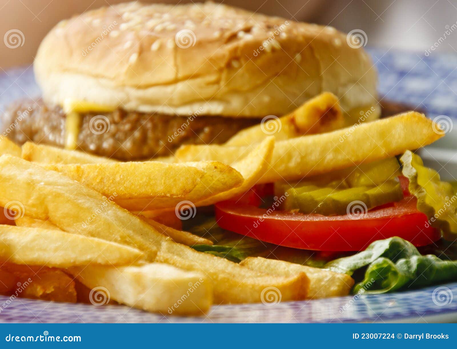 Guld- franska småfiskar för cheeseburger. Knipan för bruna småfiskar för cheeseburgeren för bakgrund skivar den guld- franska tomaten